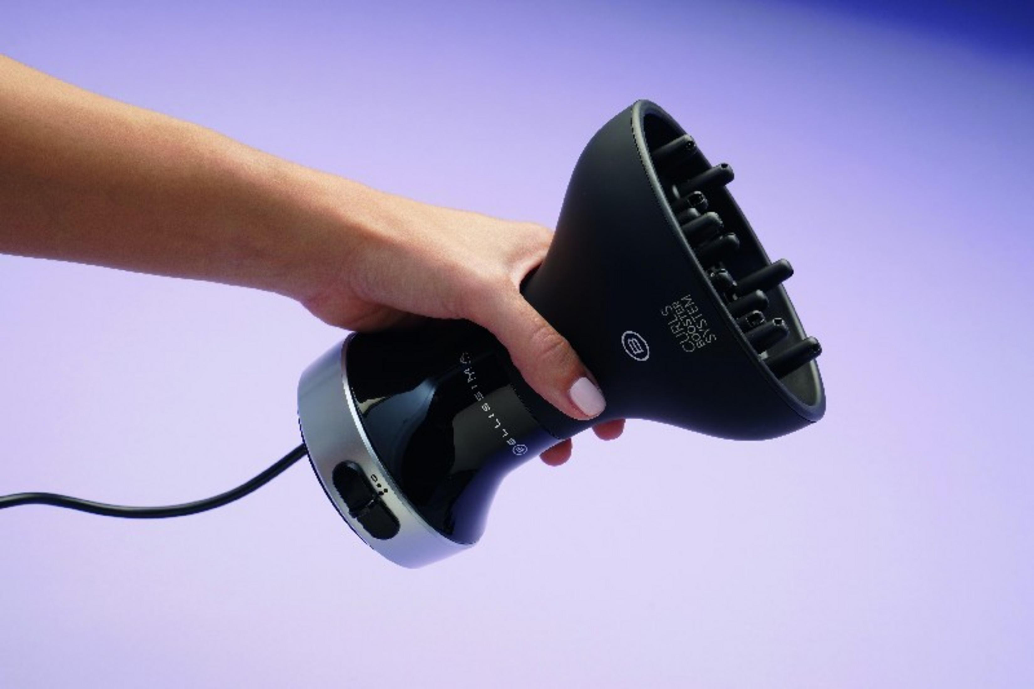 Una mano tiene un diffusore nero per asciugacapelli.