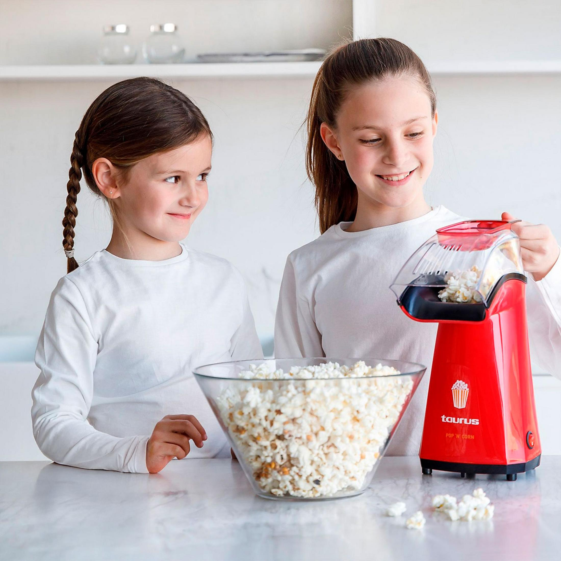 Due bambine con una macchina per popcorn e una ciotola di popcorn.