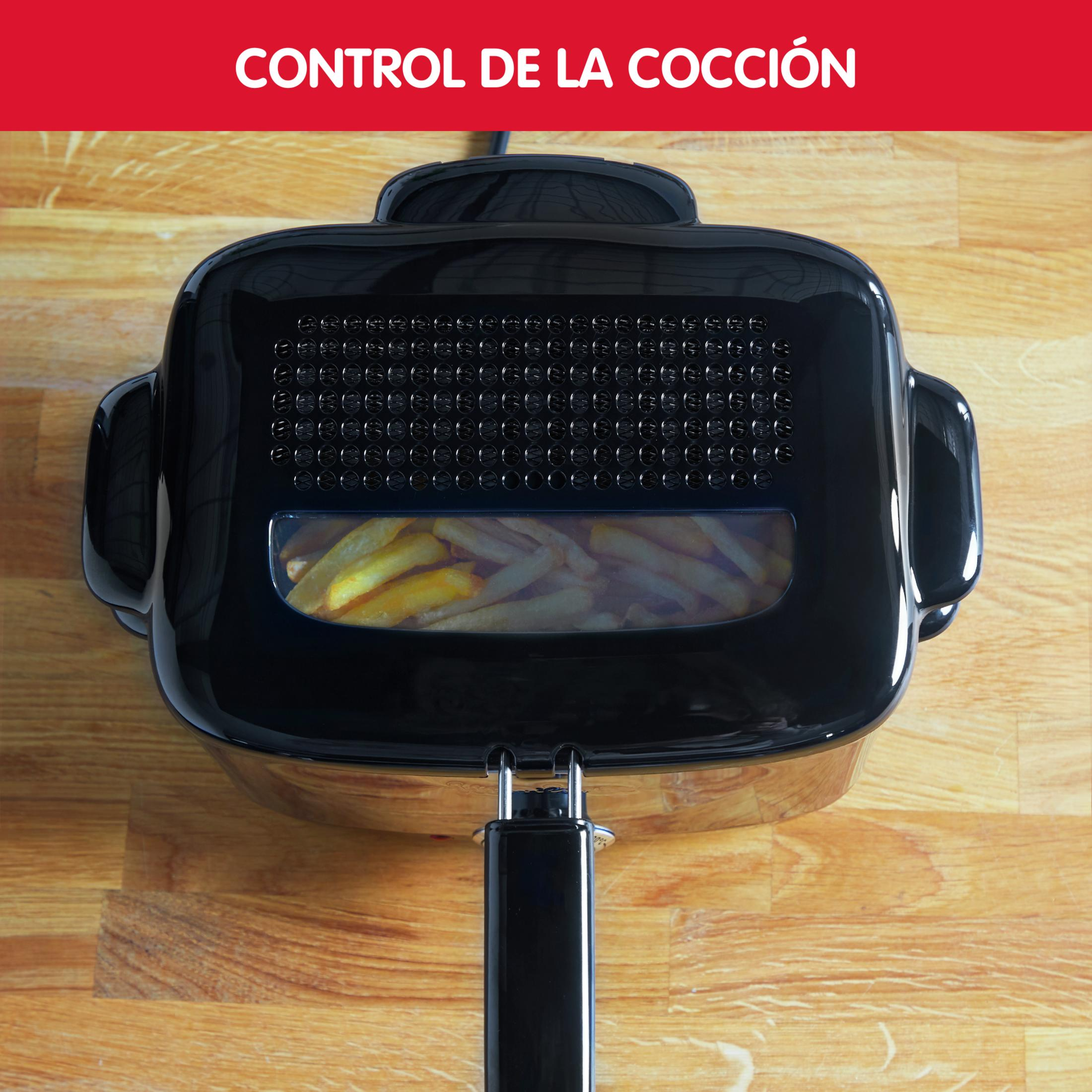 A black air fryer basket filled with french fries, resting on a wooden surface.