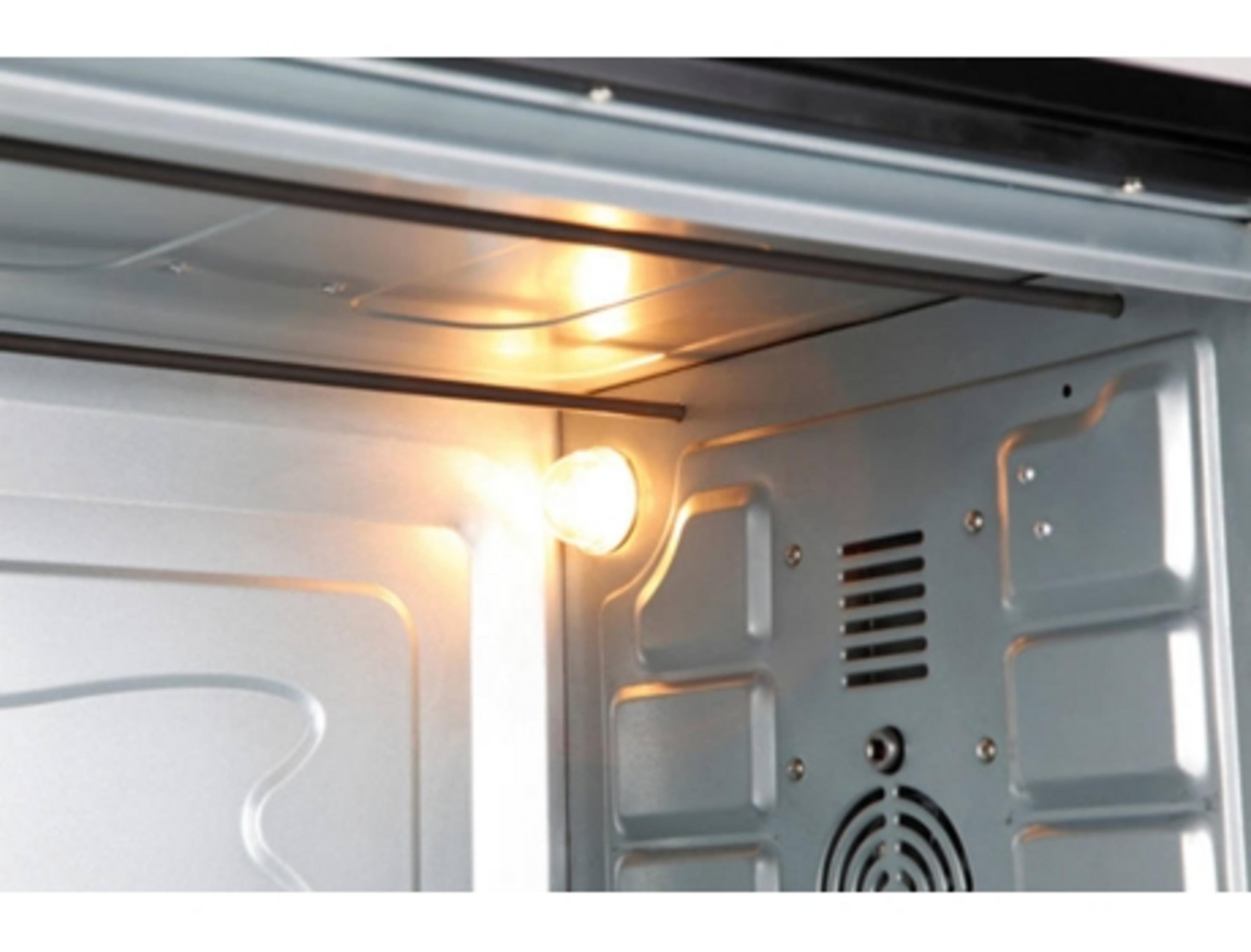 El interior de un horno con luz encendida y elementos calefactores.
