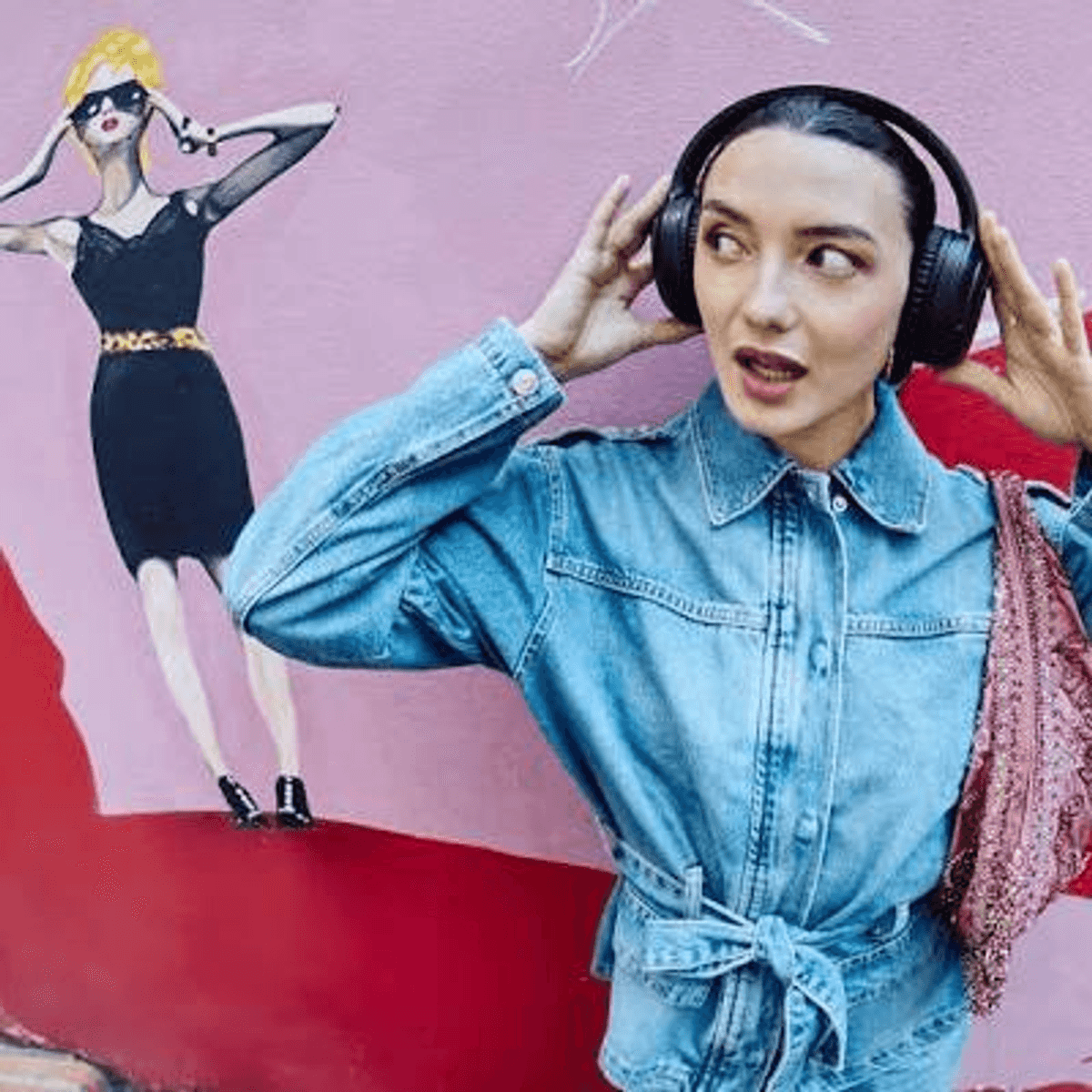 Donna con cuffie davanti a murale con figura di moda.