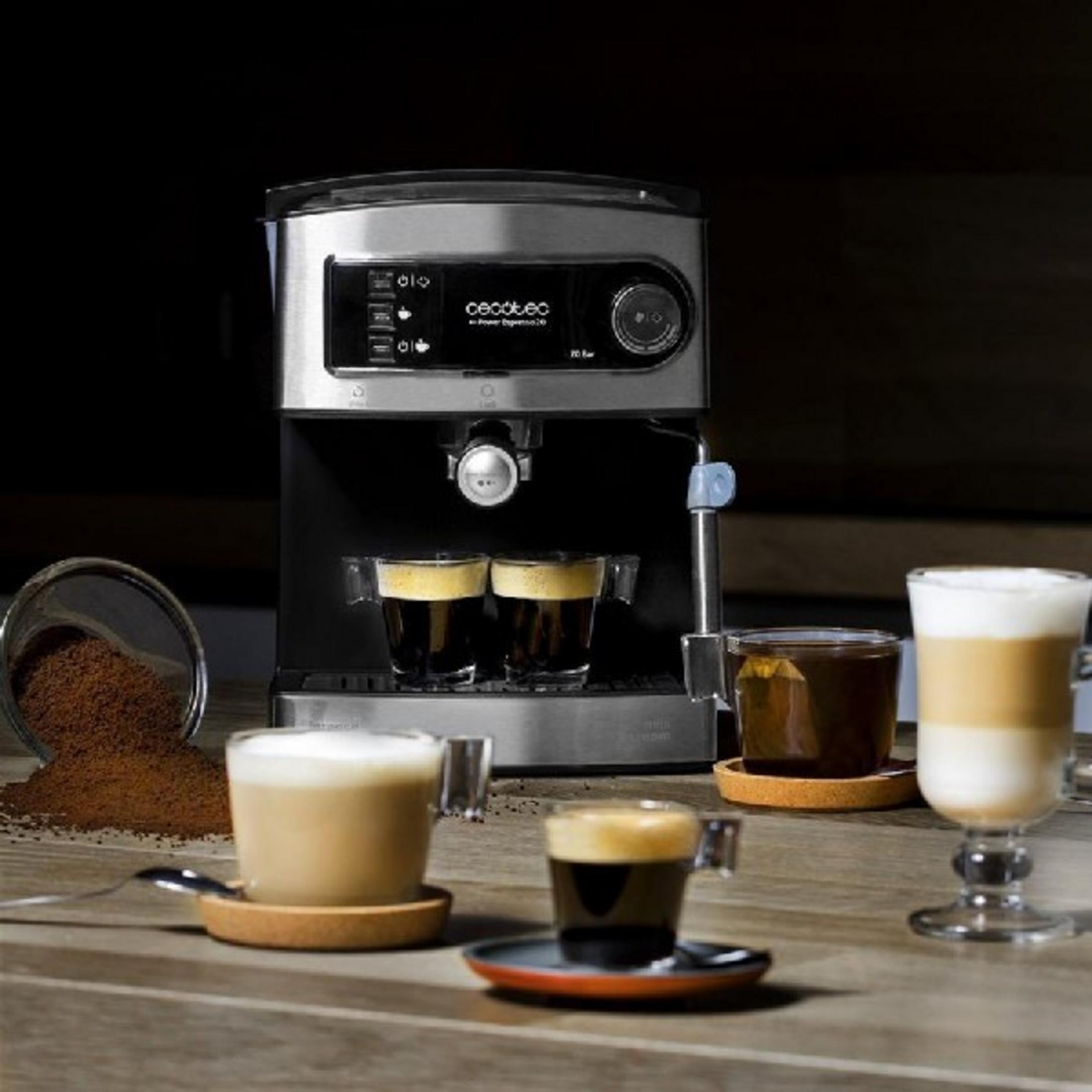 Macchina per espresso con quattro caffè e fondi di caffè accanto.