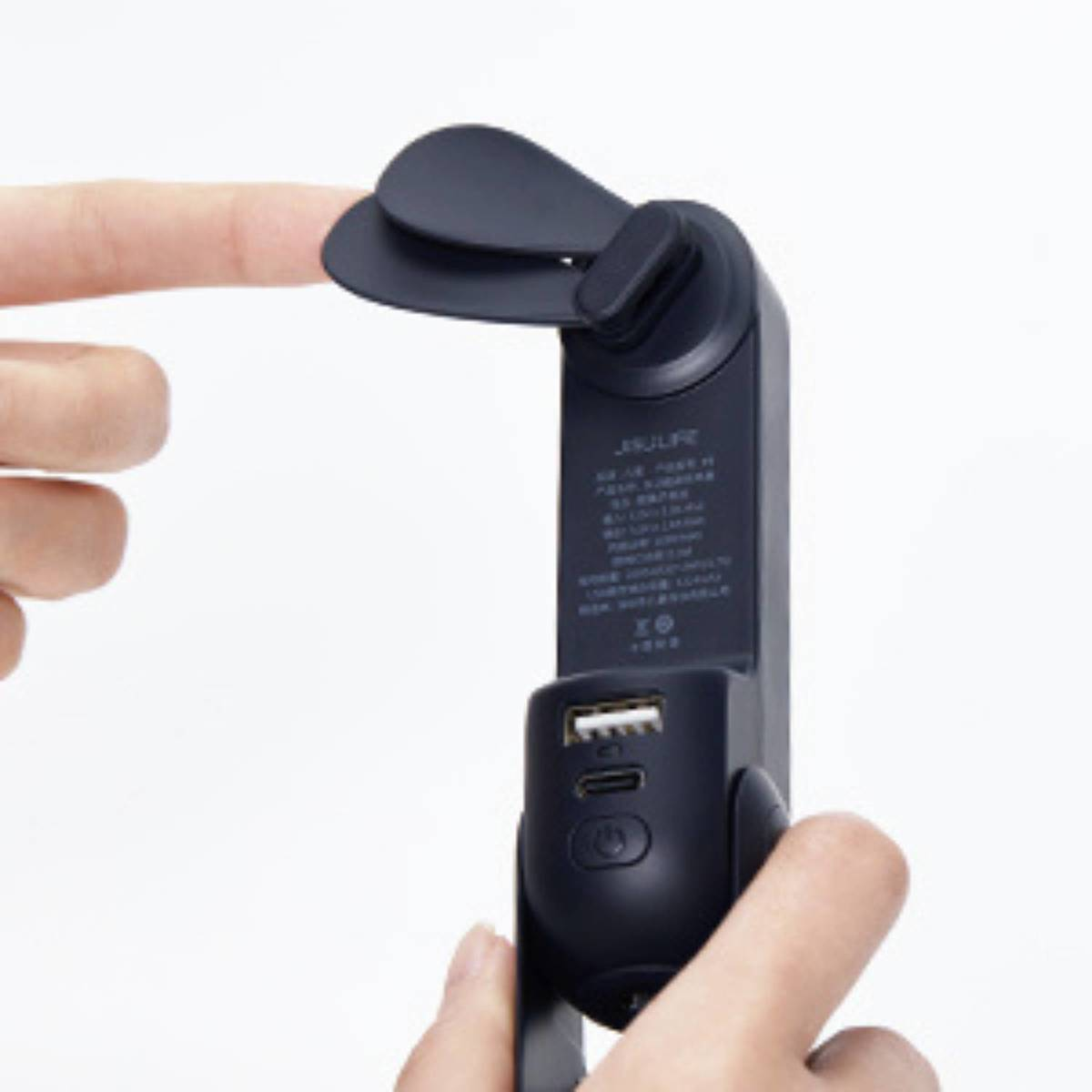 Finger berührt ein schwarzes, tragbares Lüftergerät mit USB-Anschlüssen und einem Ein-/Ausschalter.