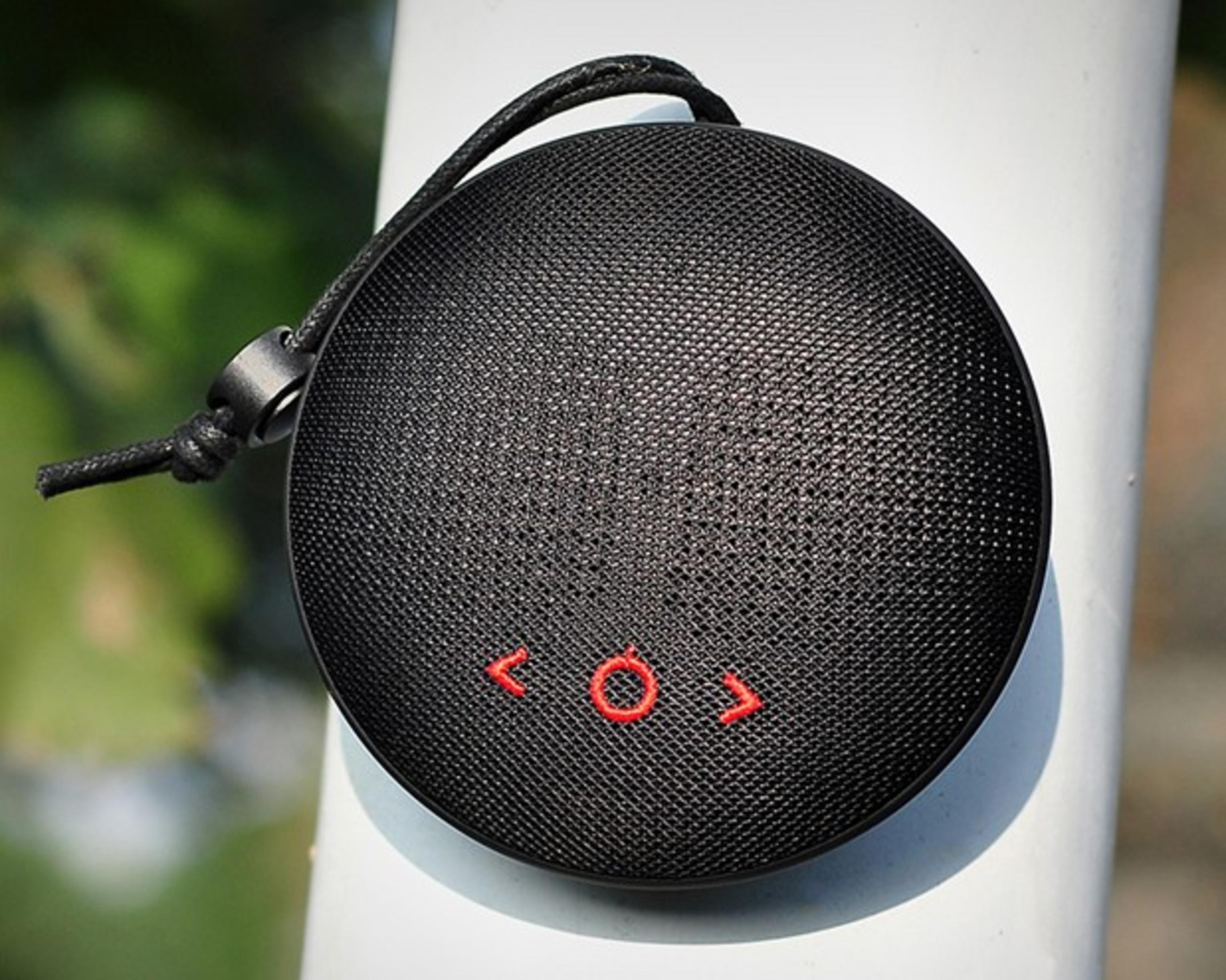 Altavoz redondo negro con símbolo rojo, sujeto a un poste blanco.