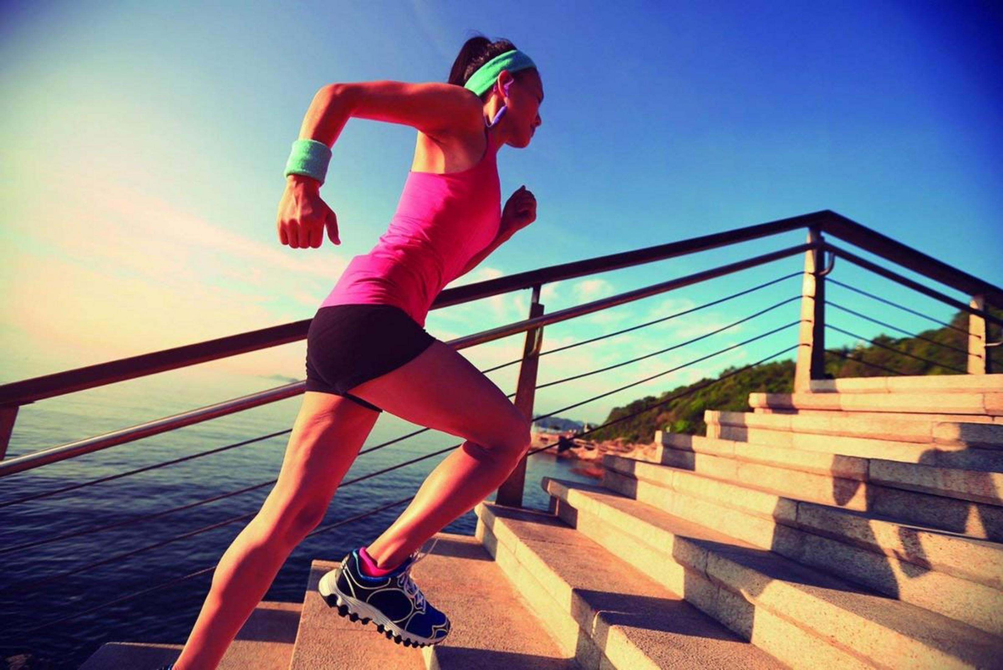 Una mujer con ropa deportiva sube escaleras de piedra, con vistas al mar.