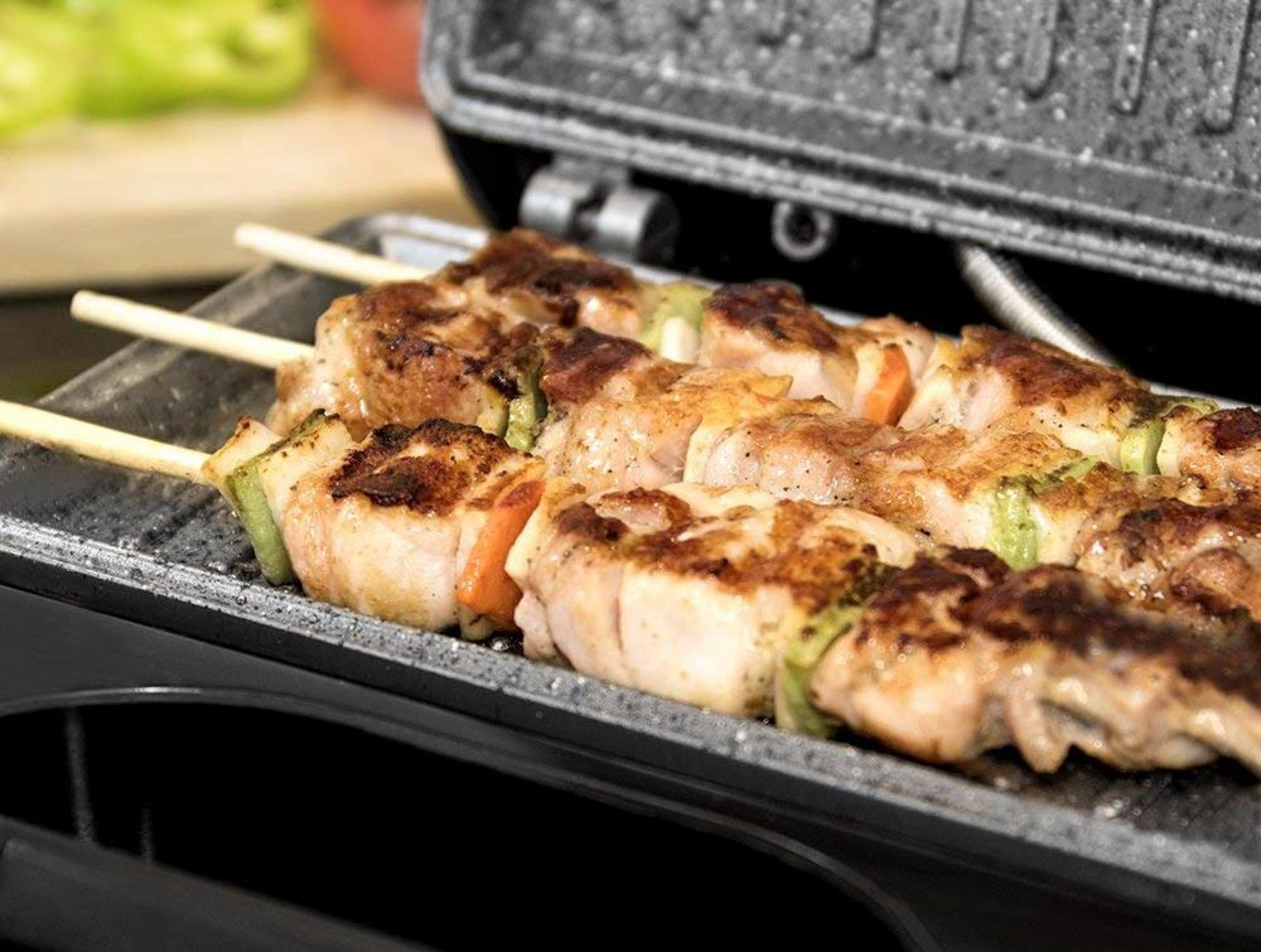 Spiedini di pollo con verdure su una griglia.