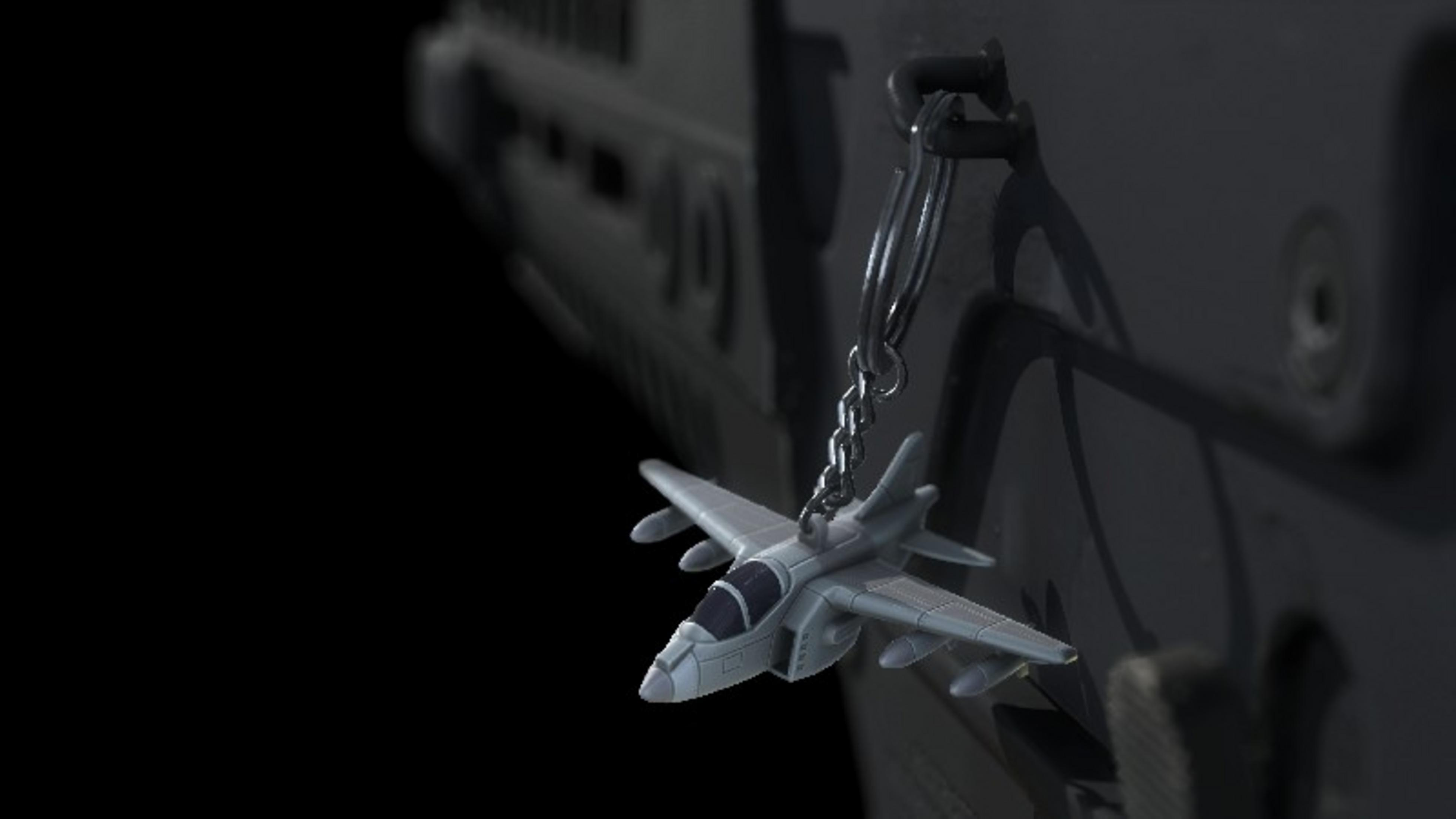 Un portachiavi aereo grigio pende da una catena su sfondo scuro.