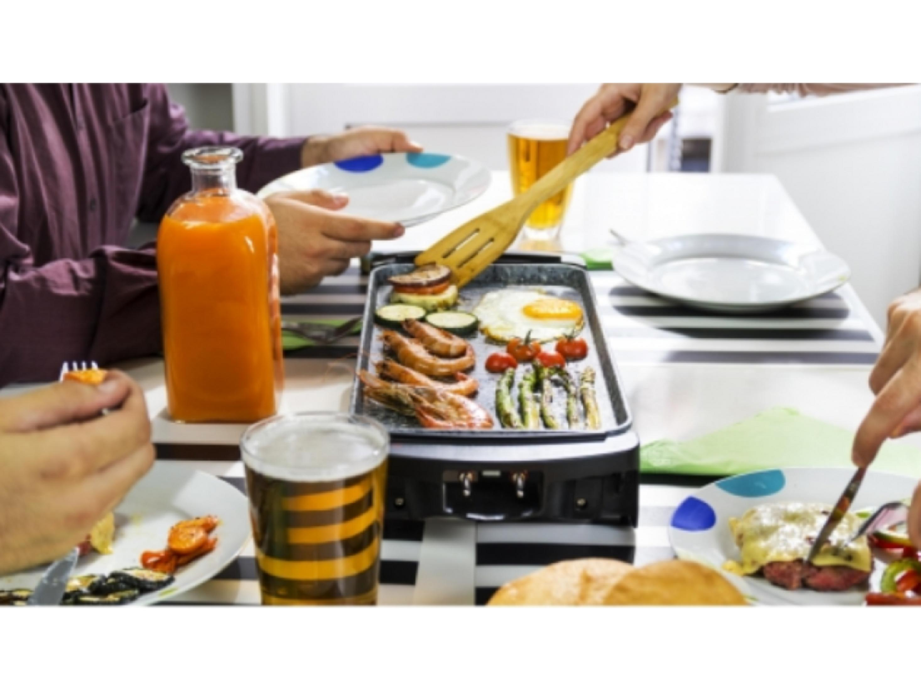 People eat at a table with grilled shrimp, asparagus, egg, and juice.