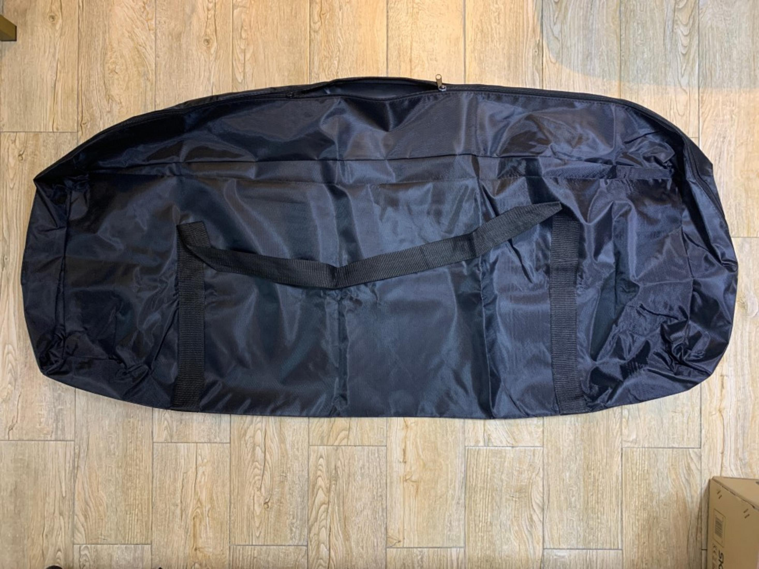 Bolsa de tela negra con asas sobre suelo de madera.