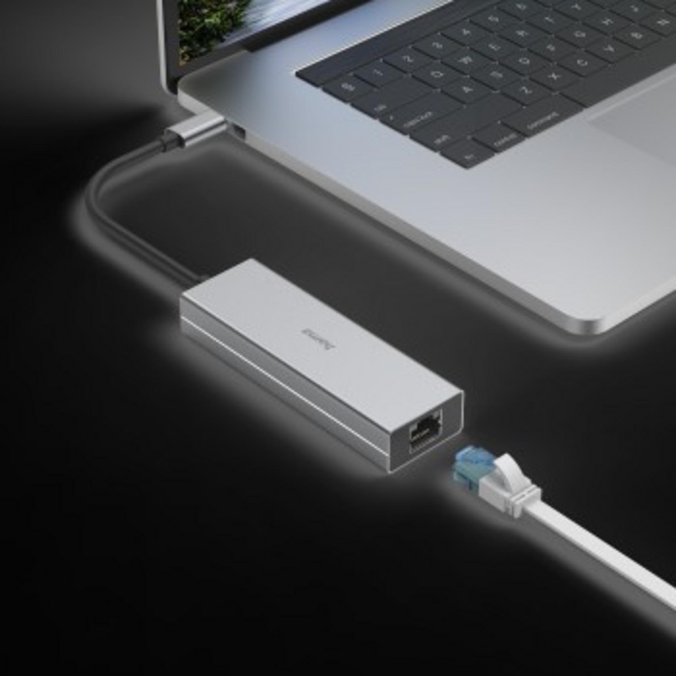 Srebrny adapter USB-C podłączony do laptopa, kabel sieciowy wpięty do adaptera.