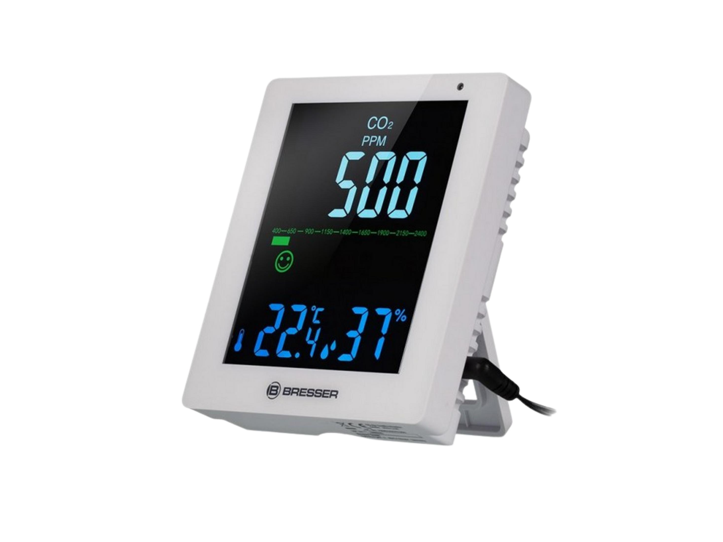 Weißes Messgerät mit blauem Display zeigt CO2, Temperatur und Luftfeuchtigkeit an.