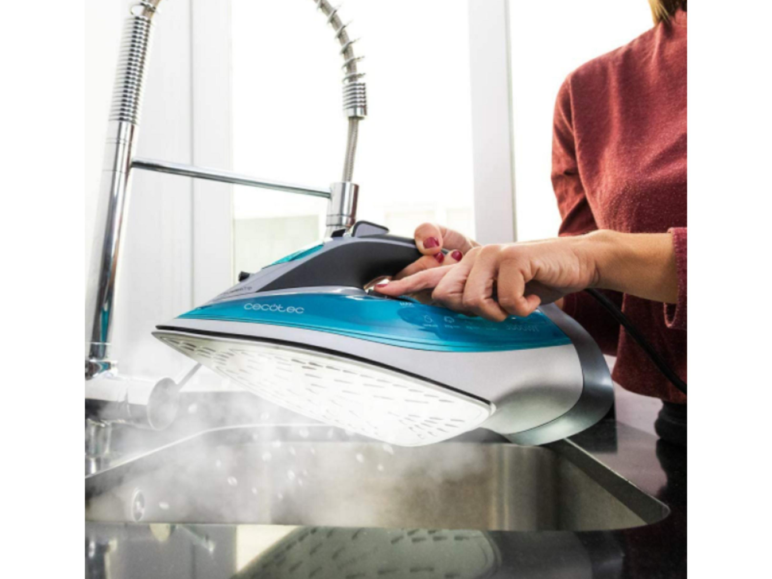 Persona llenando suela de plancha de vapor azul y blanca bajo un grifo con agua.