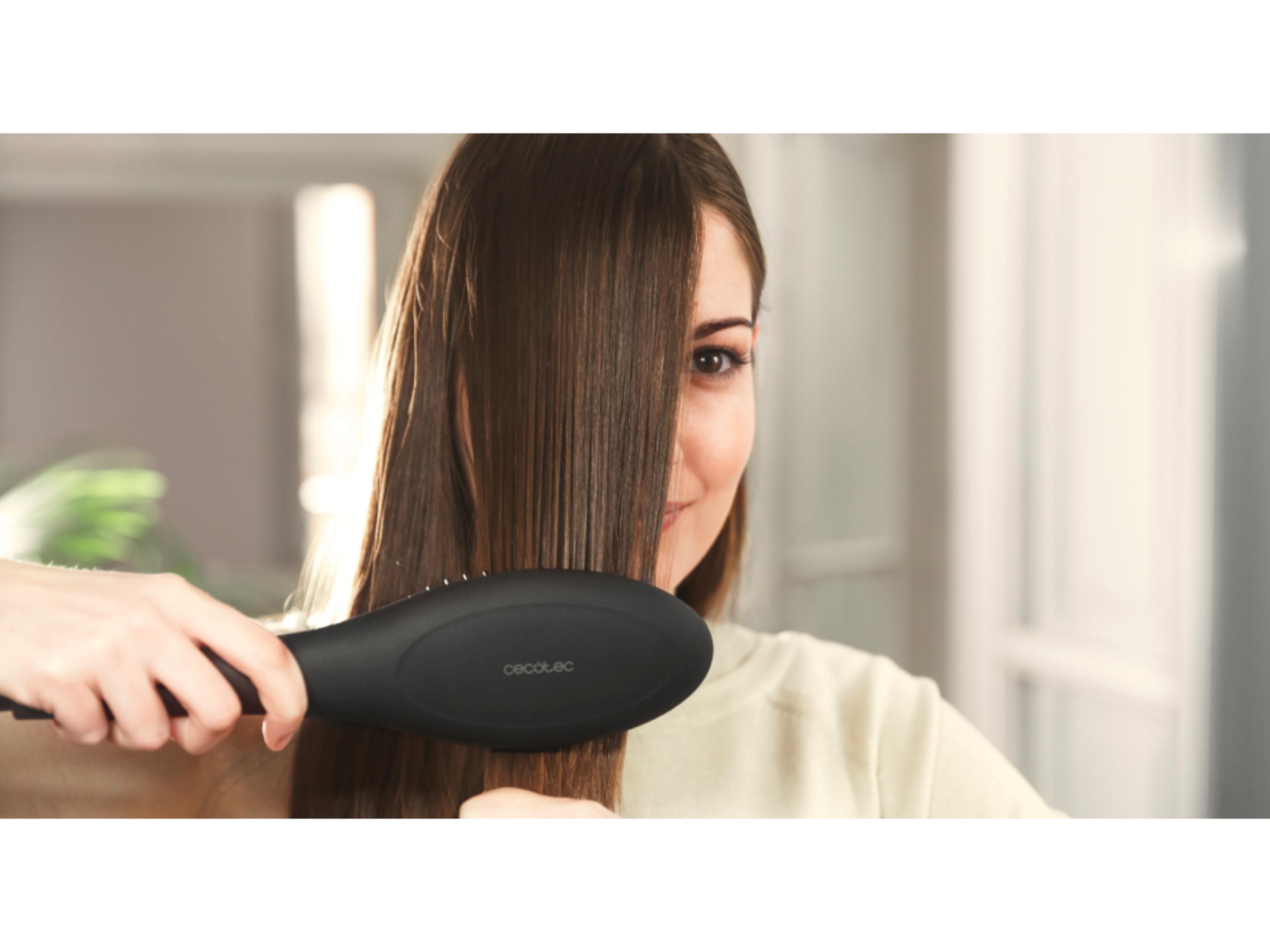 Una donna si pettina i capelli castani con una spazzola per capelli nera.