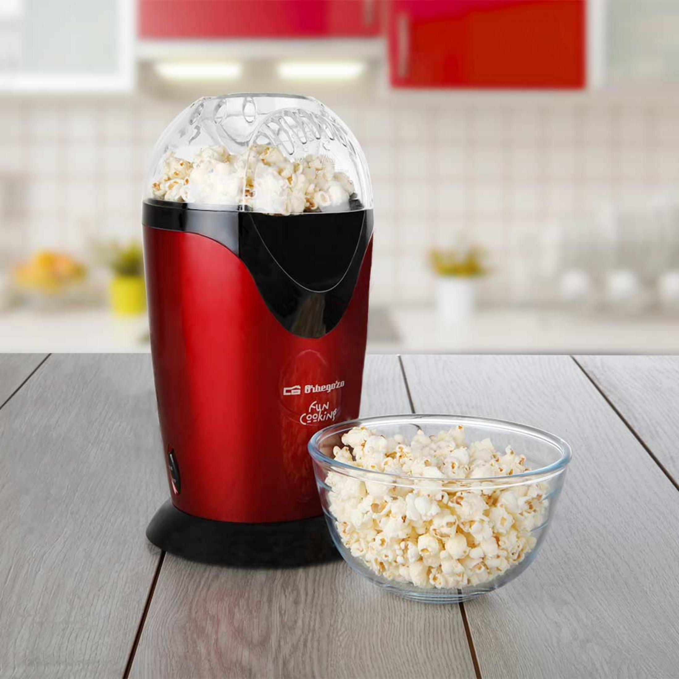 Máquina de palomitas roja con palomitas recién hechas en un bol de cristal.