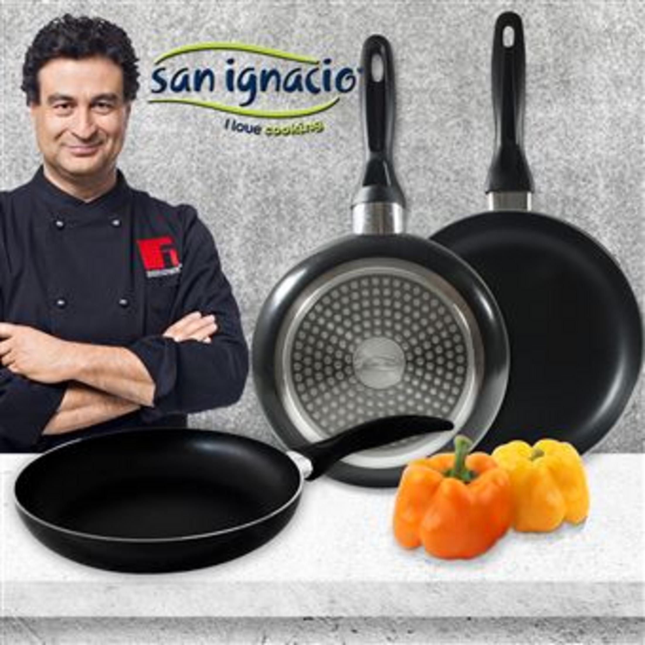 Un chef está ante sartenes, con pimientos al lado.