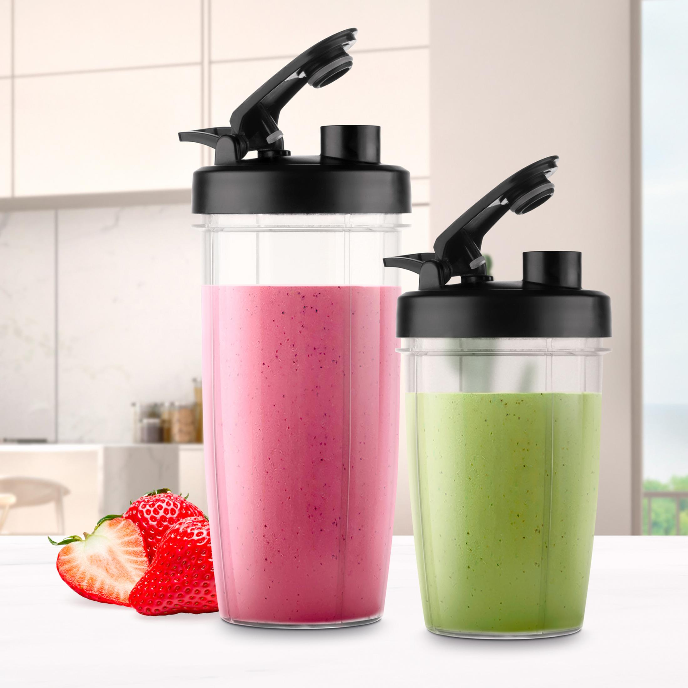 Due shaker con coperchio, uno con frullato rosa, uno con frullato verde. Fragole a sinistra.