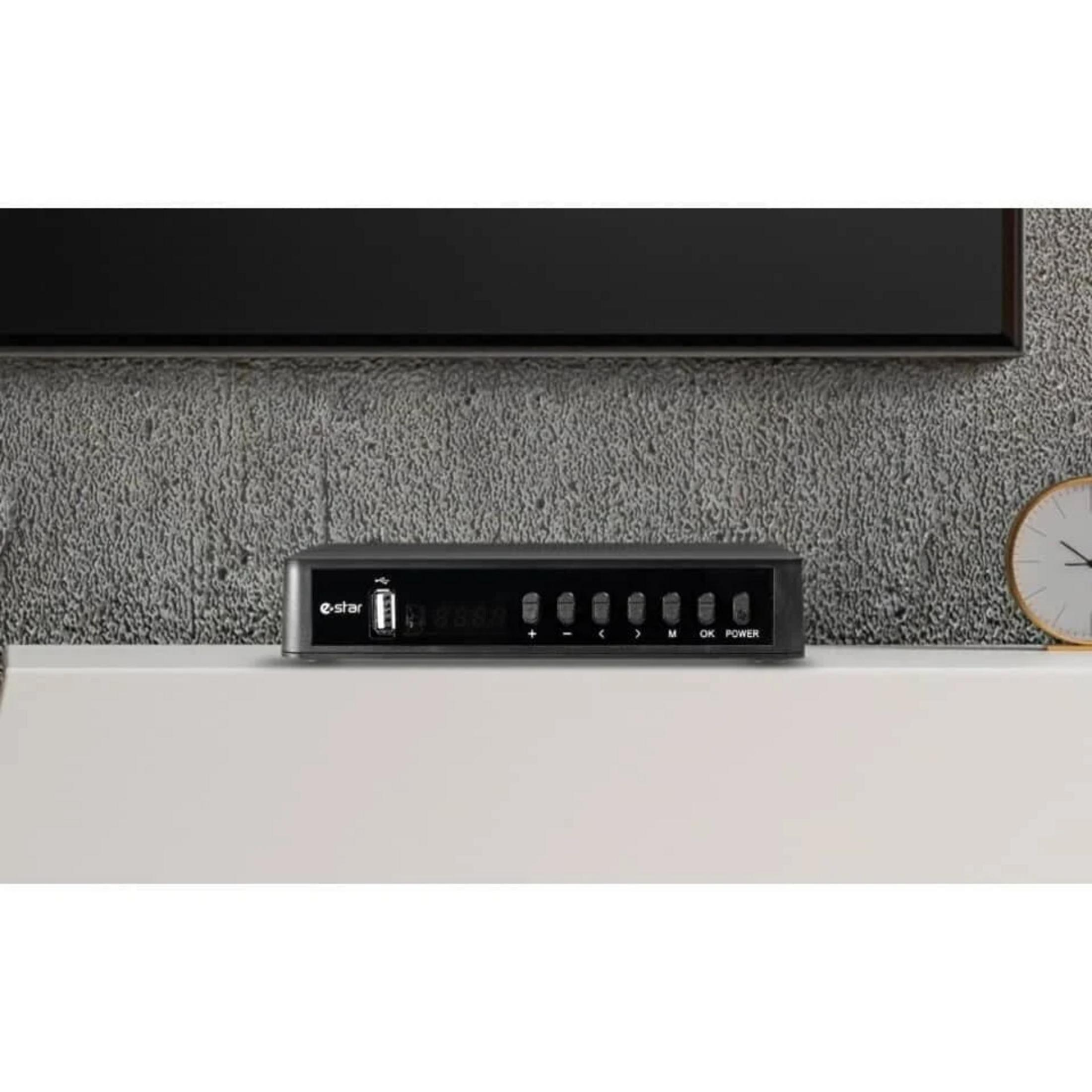 Un receptor digital negro con botones y puerto USB está sobre un estante.