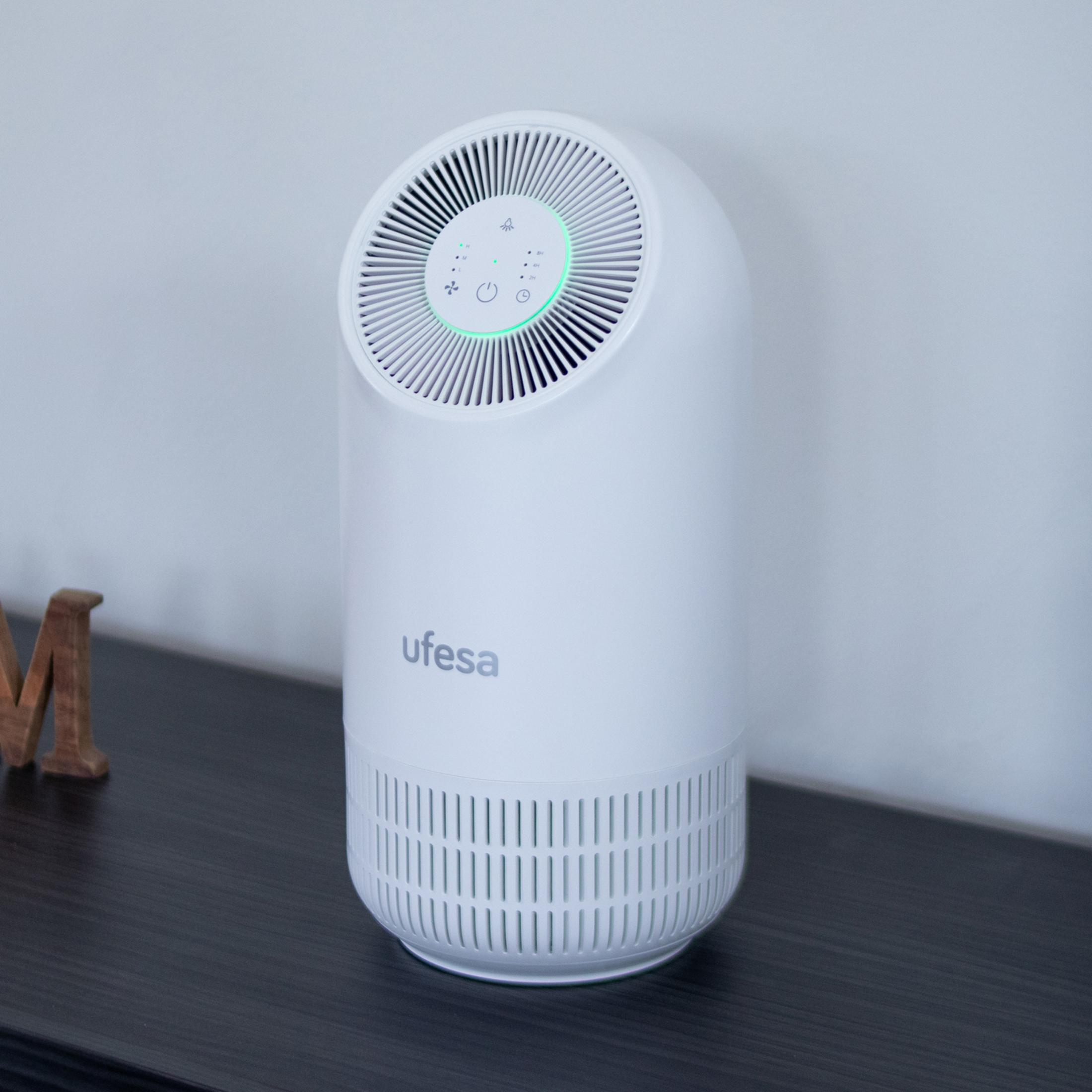 Un purificador de aire blanco con logo 'ufesa' sobre una mesa oscura.