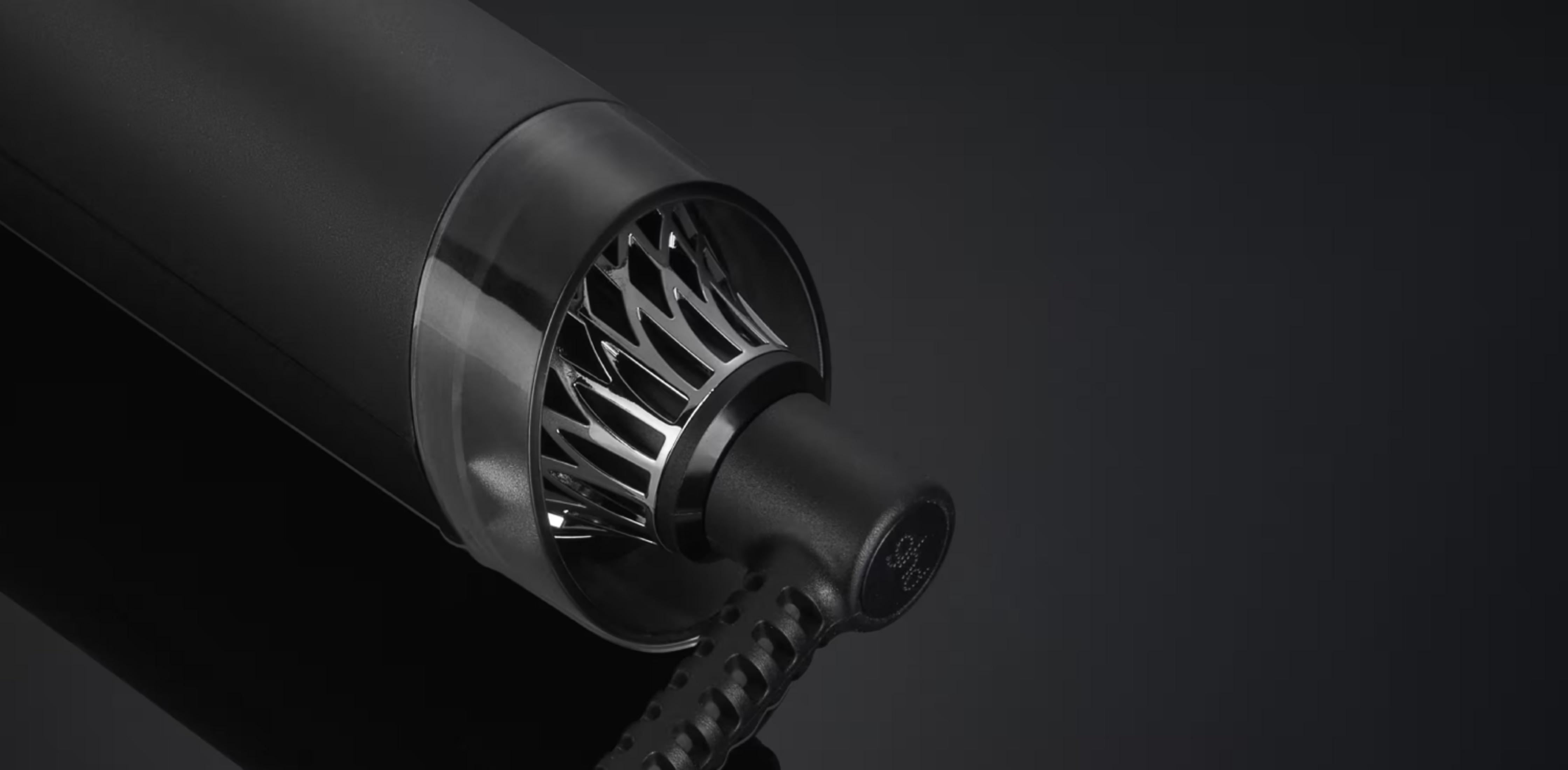 Primer plano de un secador de pelo negro con rejilla y cable plateados.