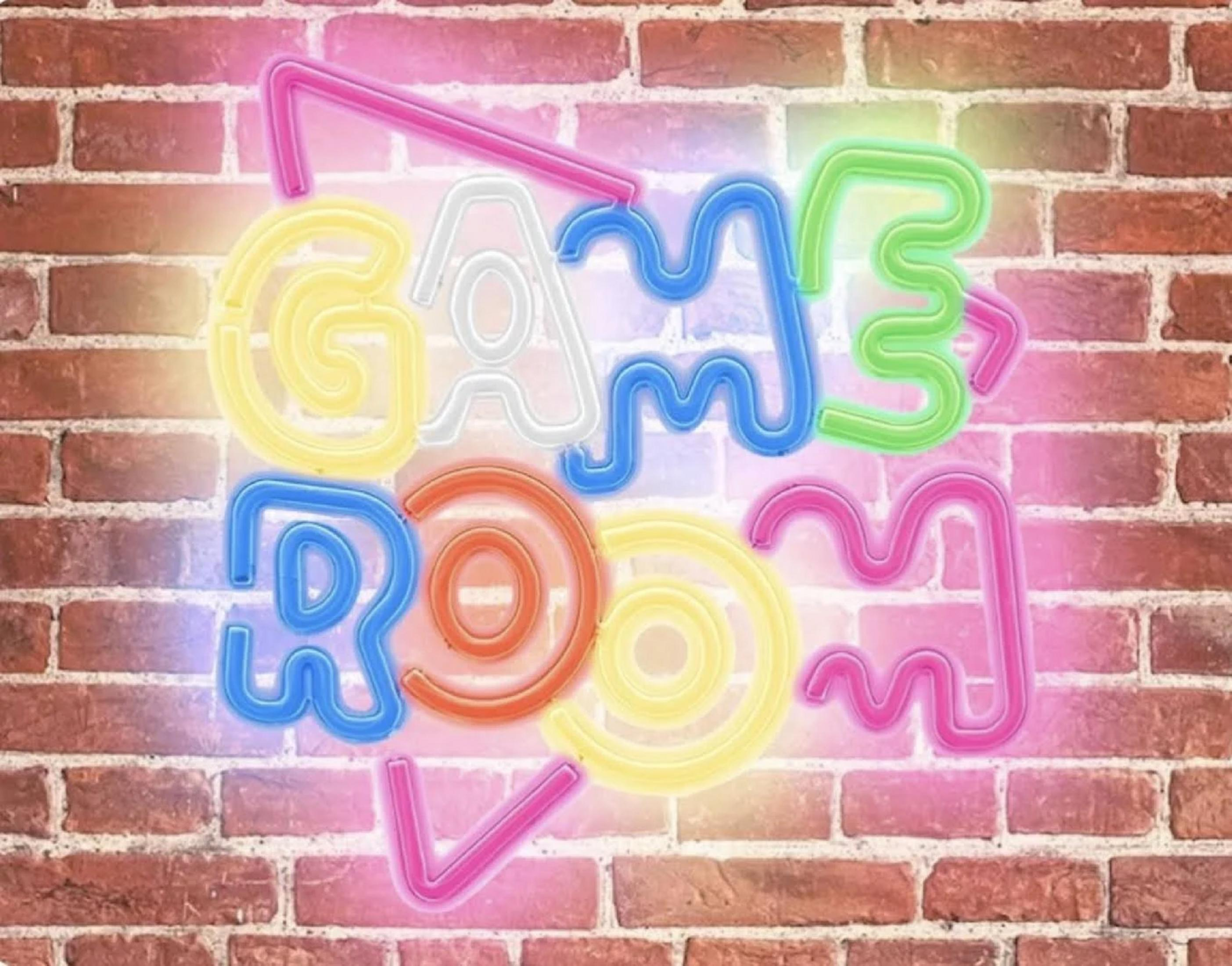 Letrero de neón en pared de ladrillos dice GAME ROOM en varios colores.