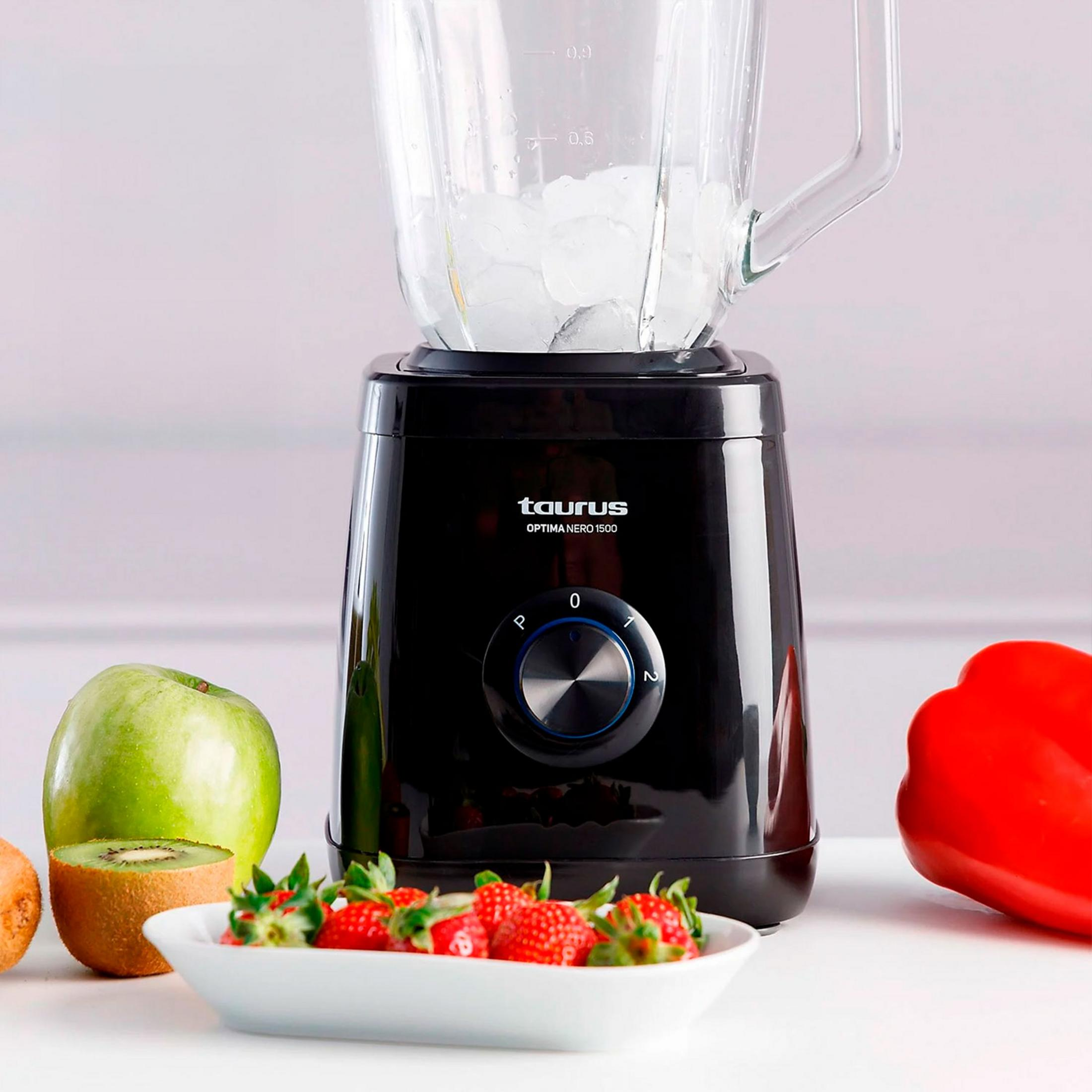 Un frullatore nero con ghiaccio, accanto a frutta e un peperone rosso.