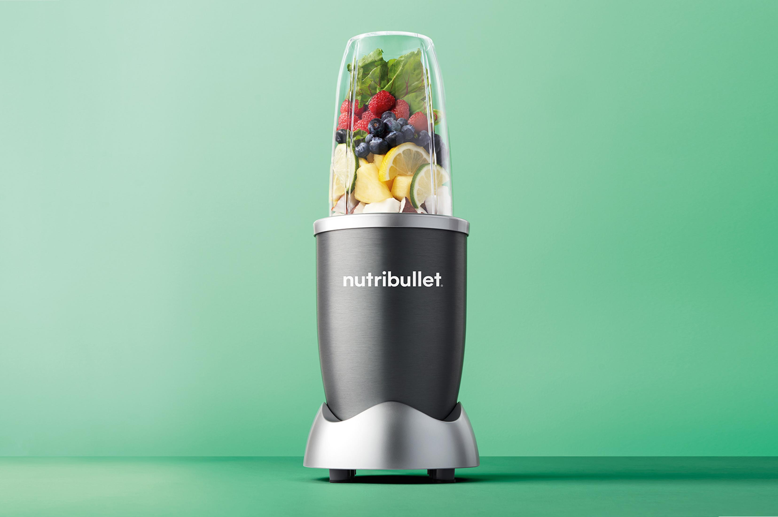 Un frullatore Nutribullet riempito con bacche, limone, ananas e verdure.