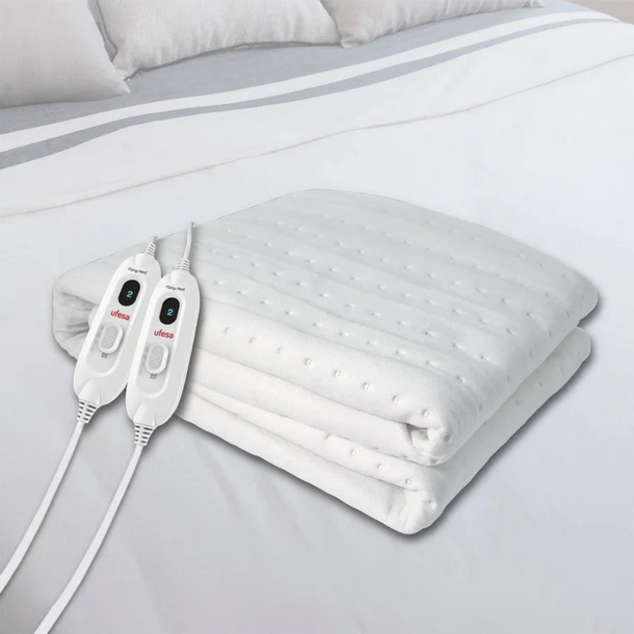 Una coperta elettrica bianca piegata con due controller bianchi che mostrano impostazioni digitali.