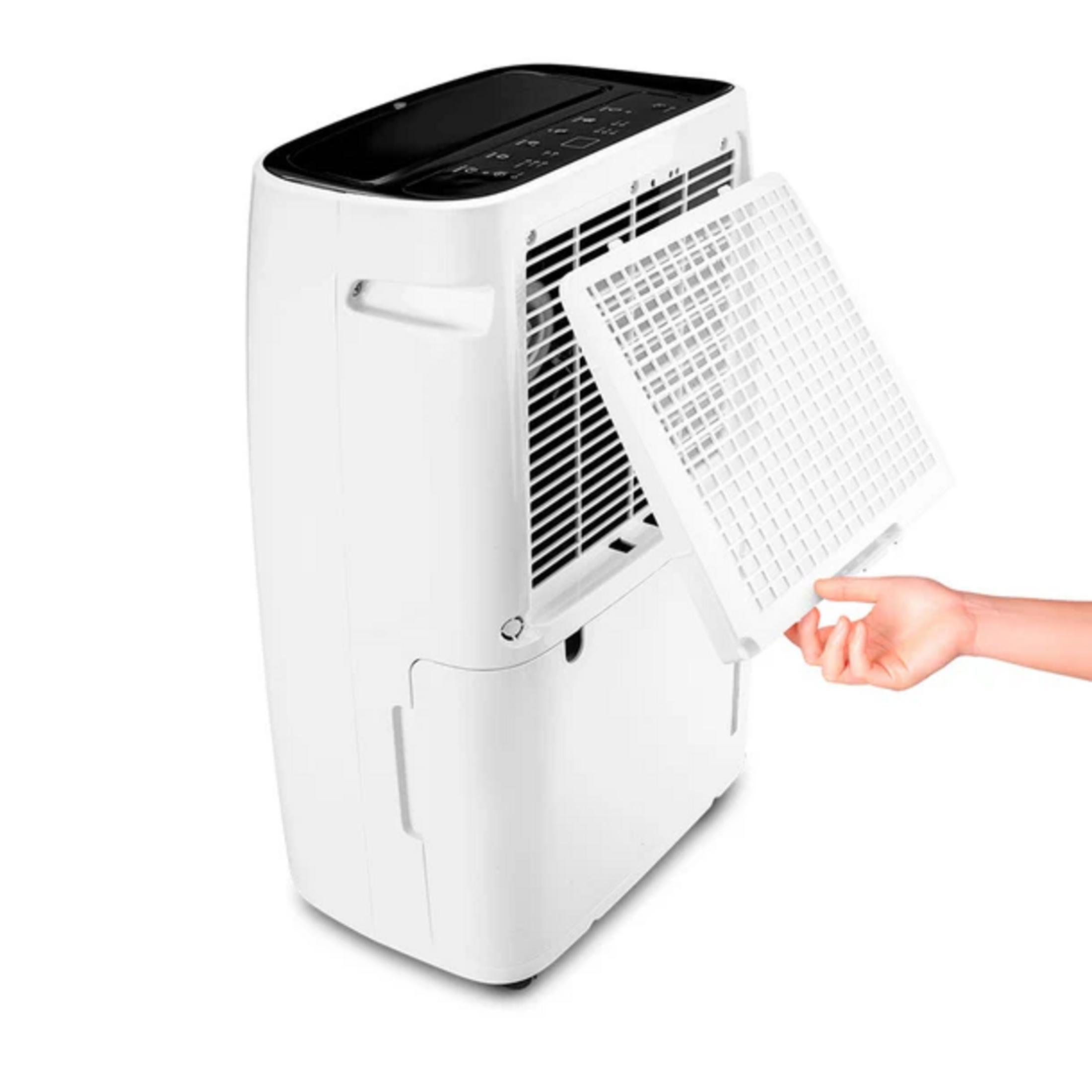 Una mano extrae un filtro blanco de un deshumidificador blanco.