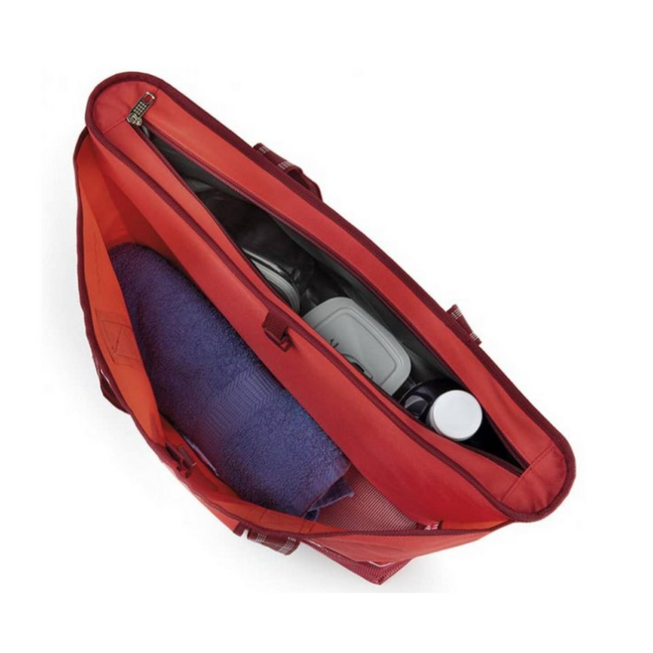 Bolsa roja con toalla azul, contenedor y botellas dentro.