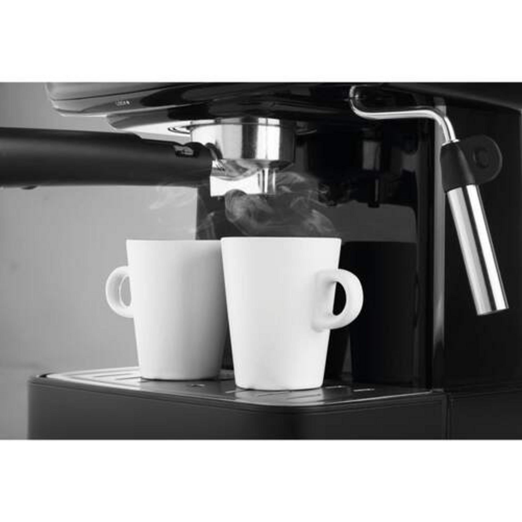 Dos tazas blancas sobre una cafetera con vapor ascendiendo.