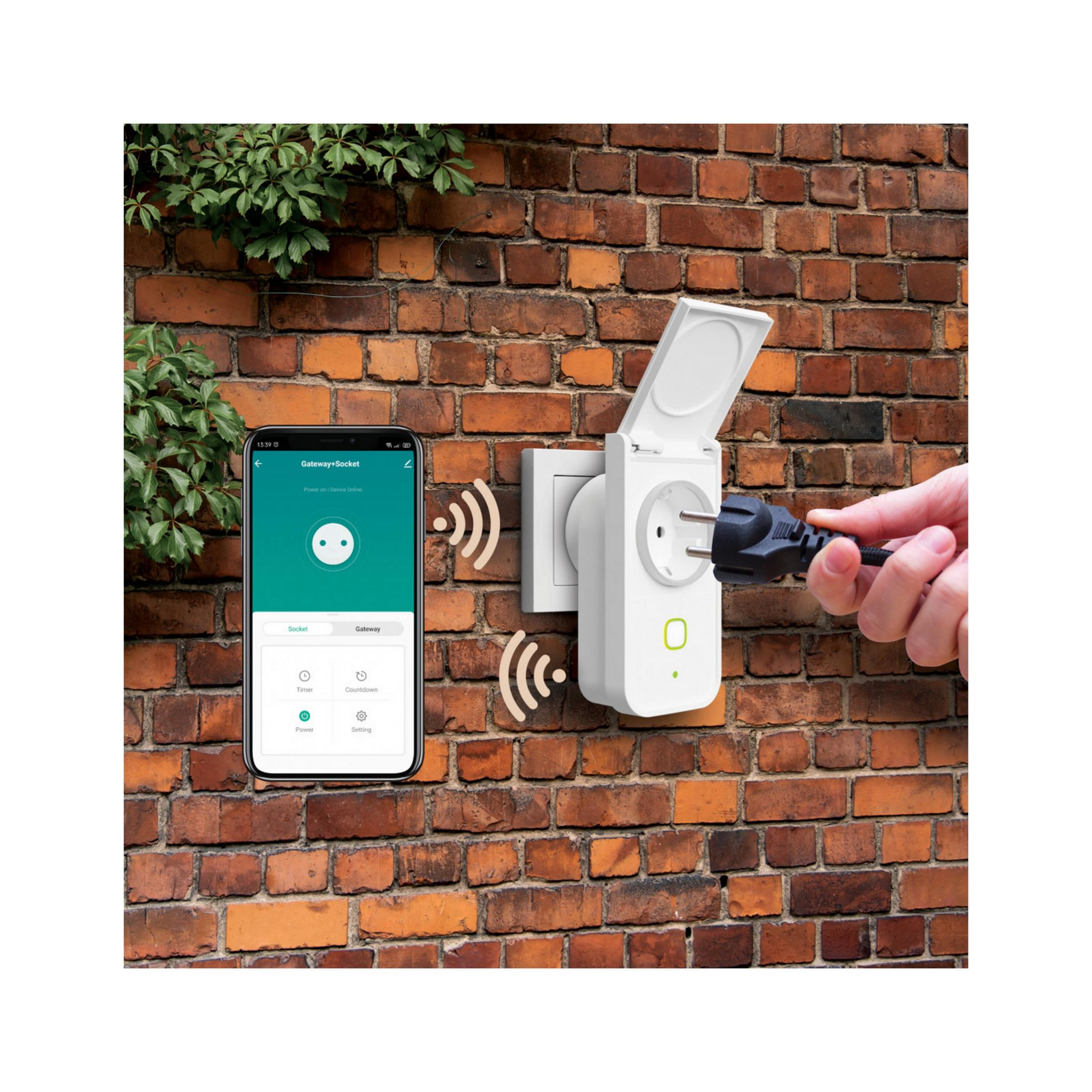 Un smartphone muestra una app con un enchufe y una toma en una pared de ladrillos.