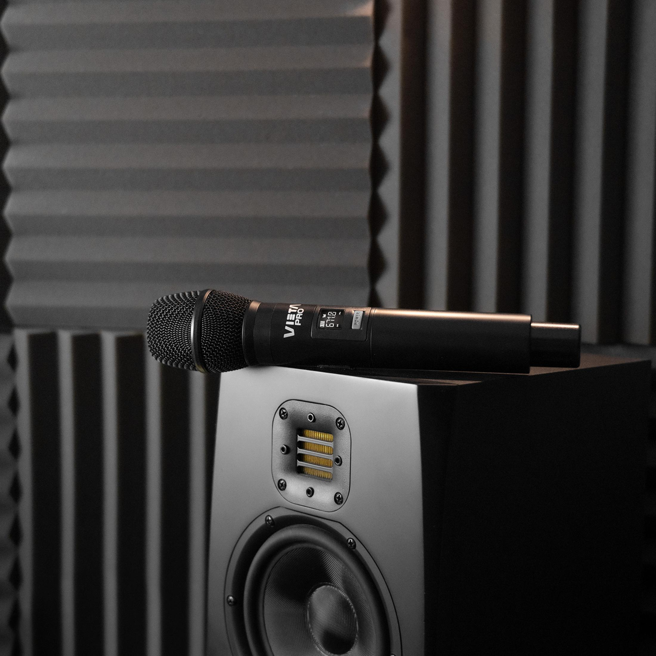 Un micrófono VISTA PRO negro descansa sobre un altavoz negro en una sala insonorizada.