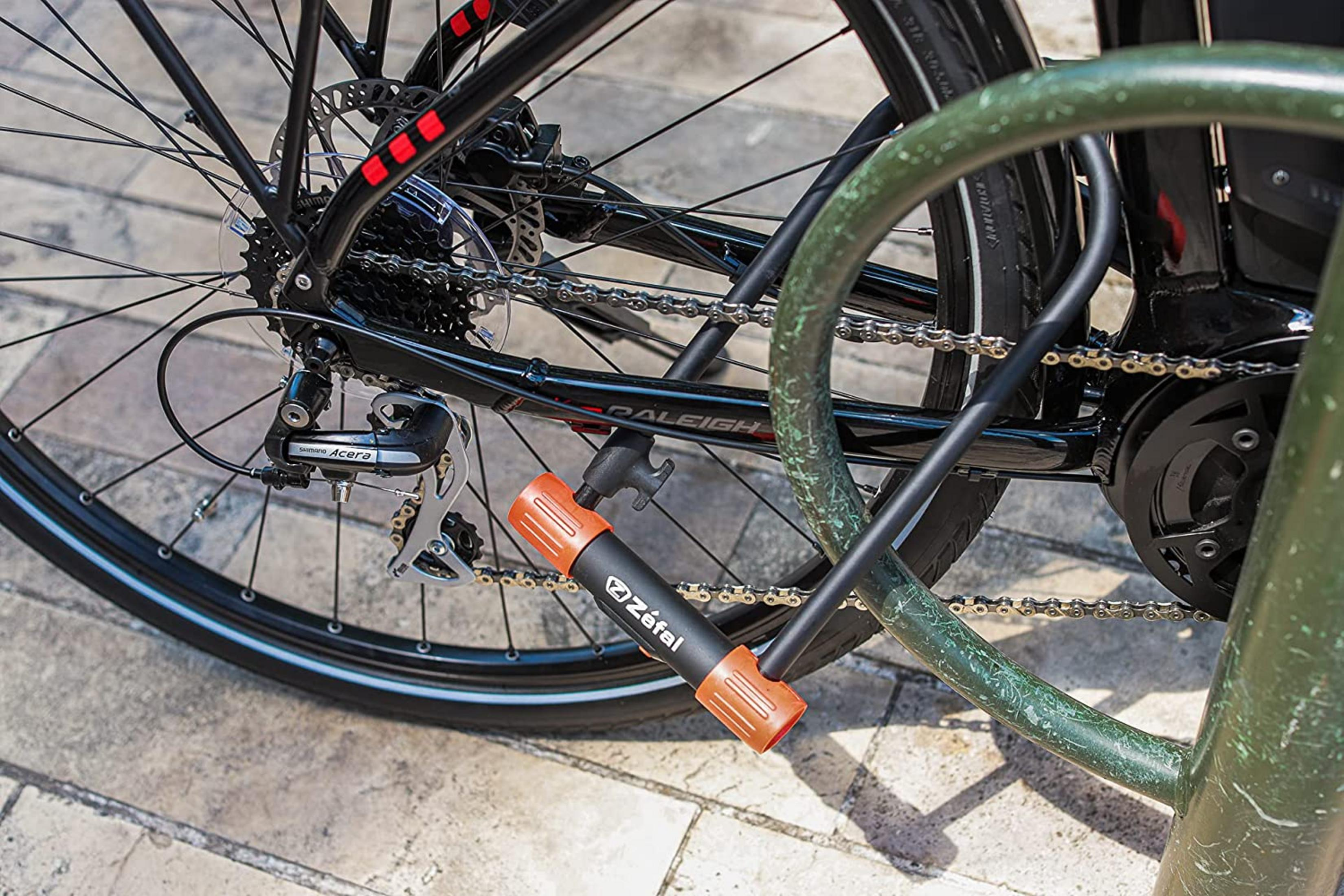 Nahaufnahme eines Fahrradschlosses mit orangen Akzenten, das an einem Fahrradrahmen befestigt ist.