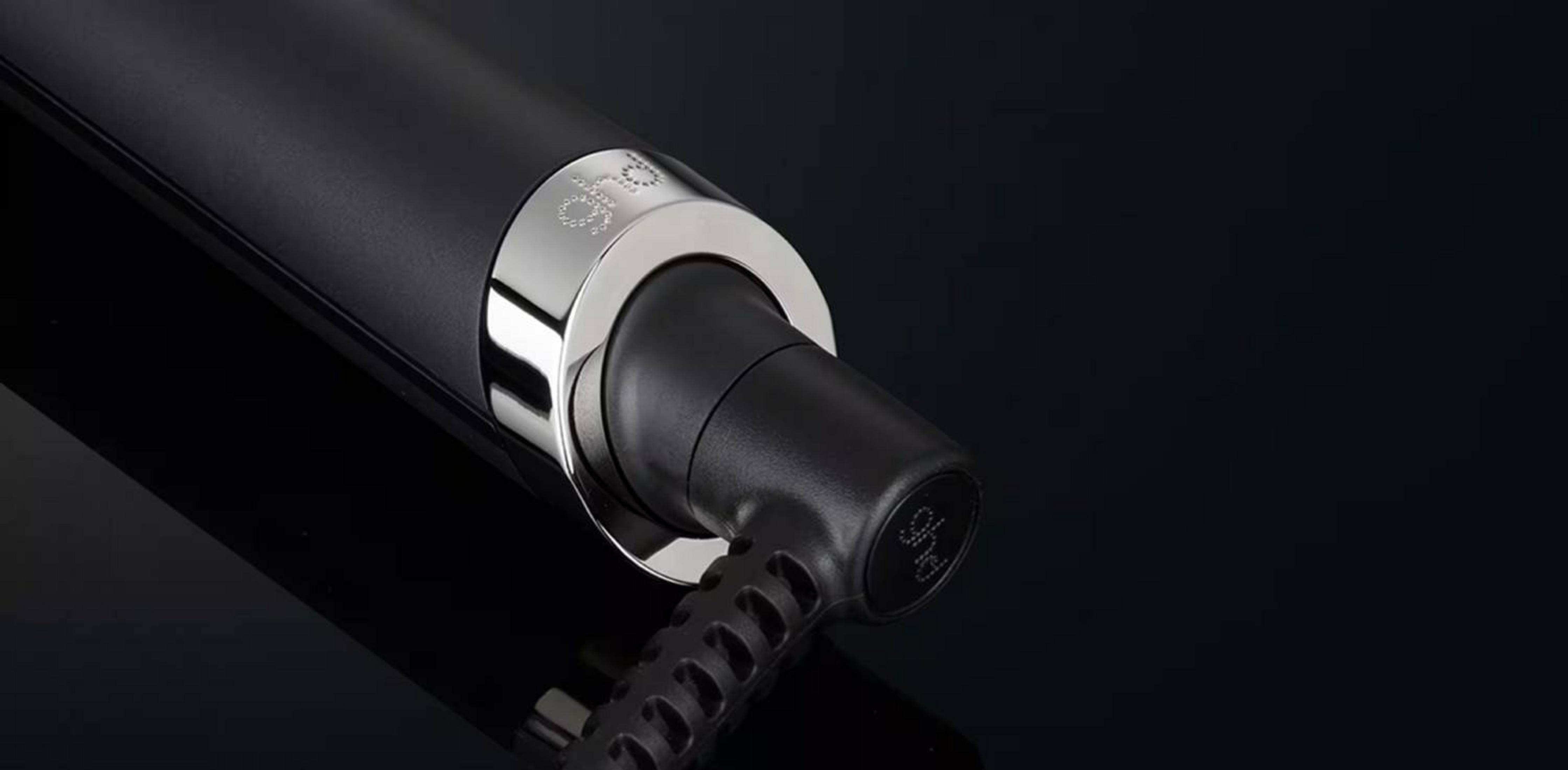 Primer plano de un secador de pelo negro con anillo plateado y logo GHD.