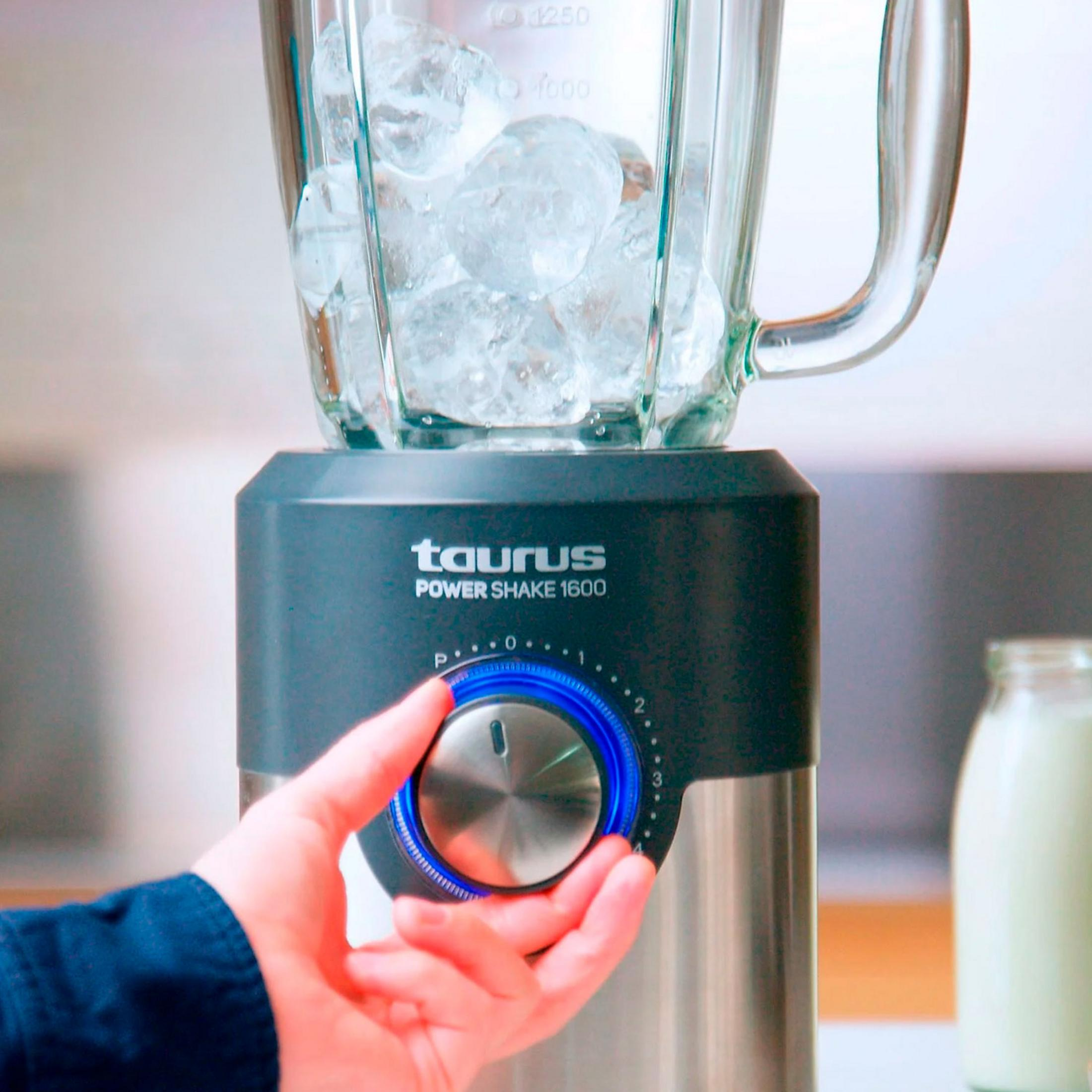 Mano gira dial en licuadora Taurus con hielo en tarro de cristal.