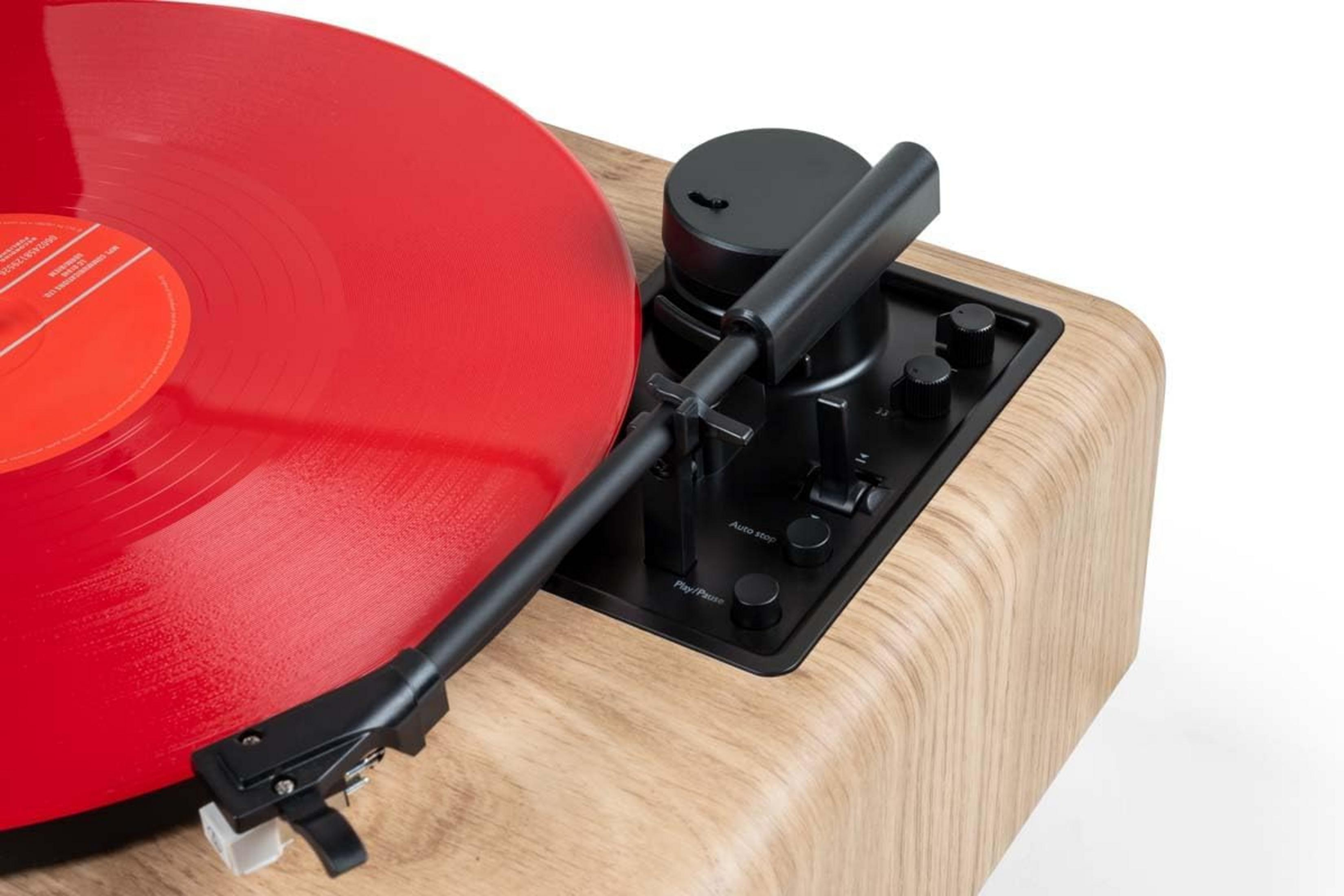 Un giradischi con disco in vinile rosso e braccio su base in legno.