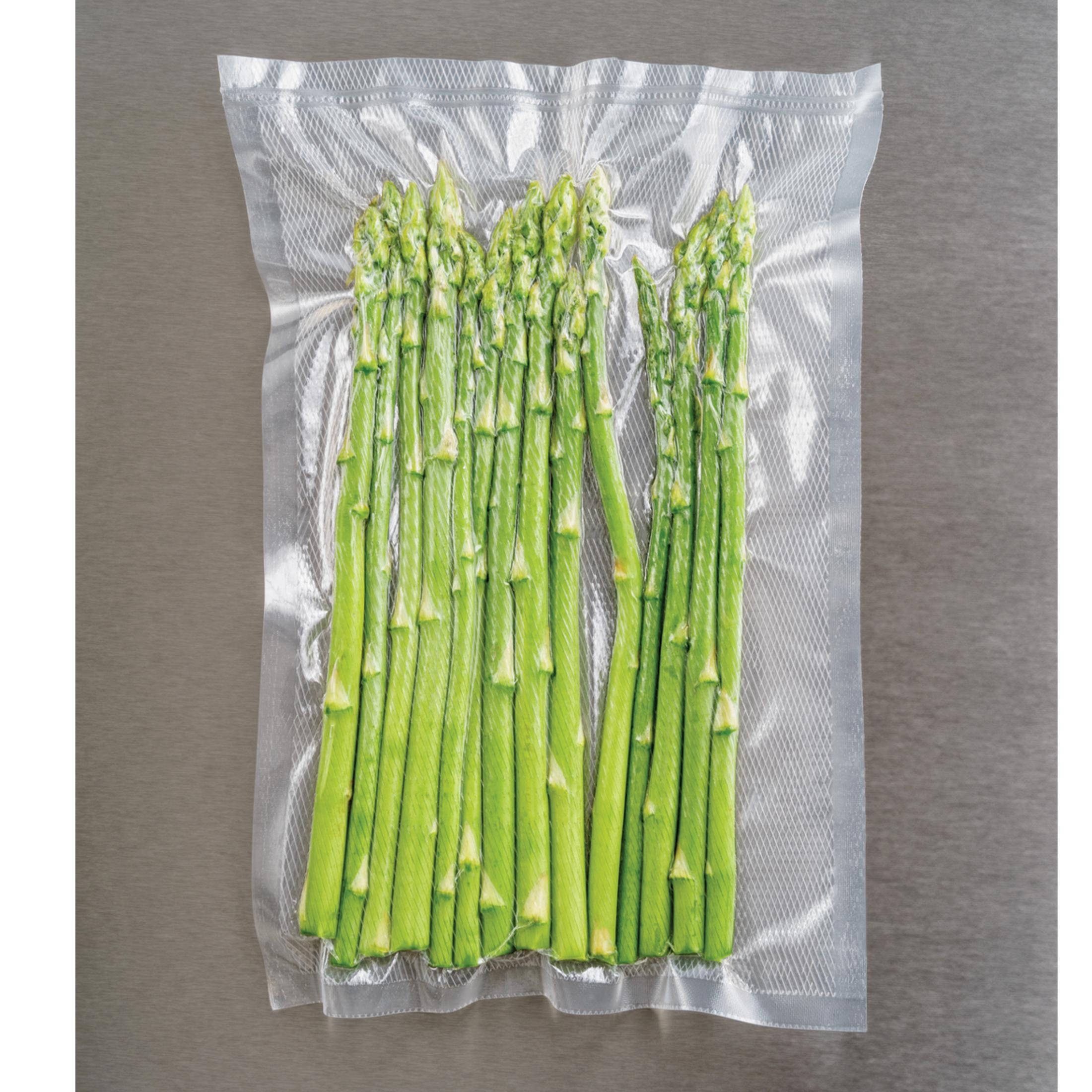 Asparagi verdi sigillati in un sacchetto sottovuoto trasparente su sfondo grigio.