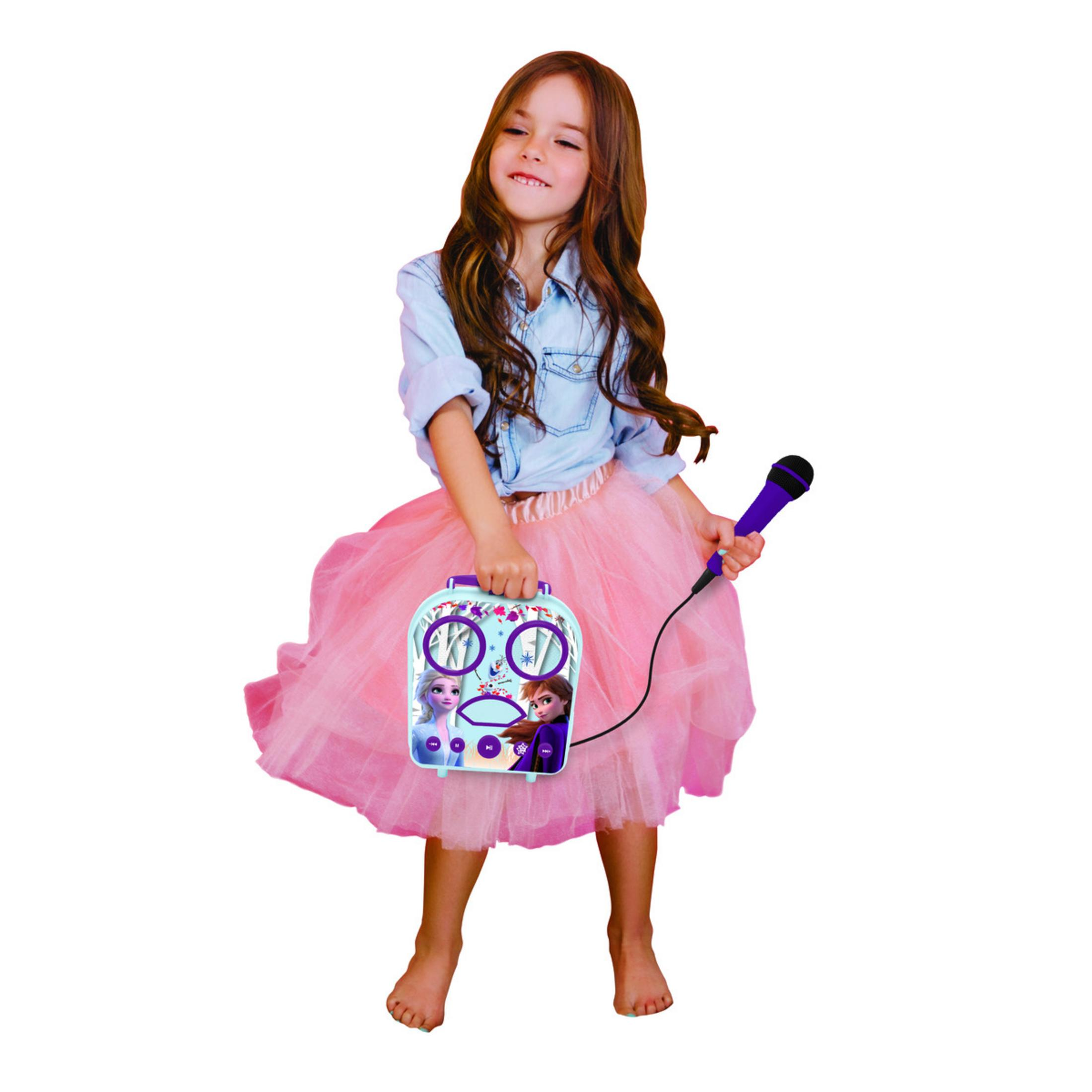 Niña con pelo largo, camisa azul y tutú rosa. Sostiene una máquina de karaoke azul con micrófono.