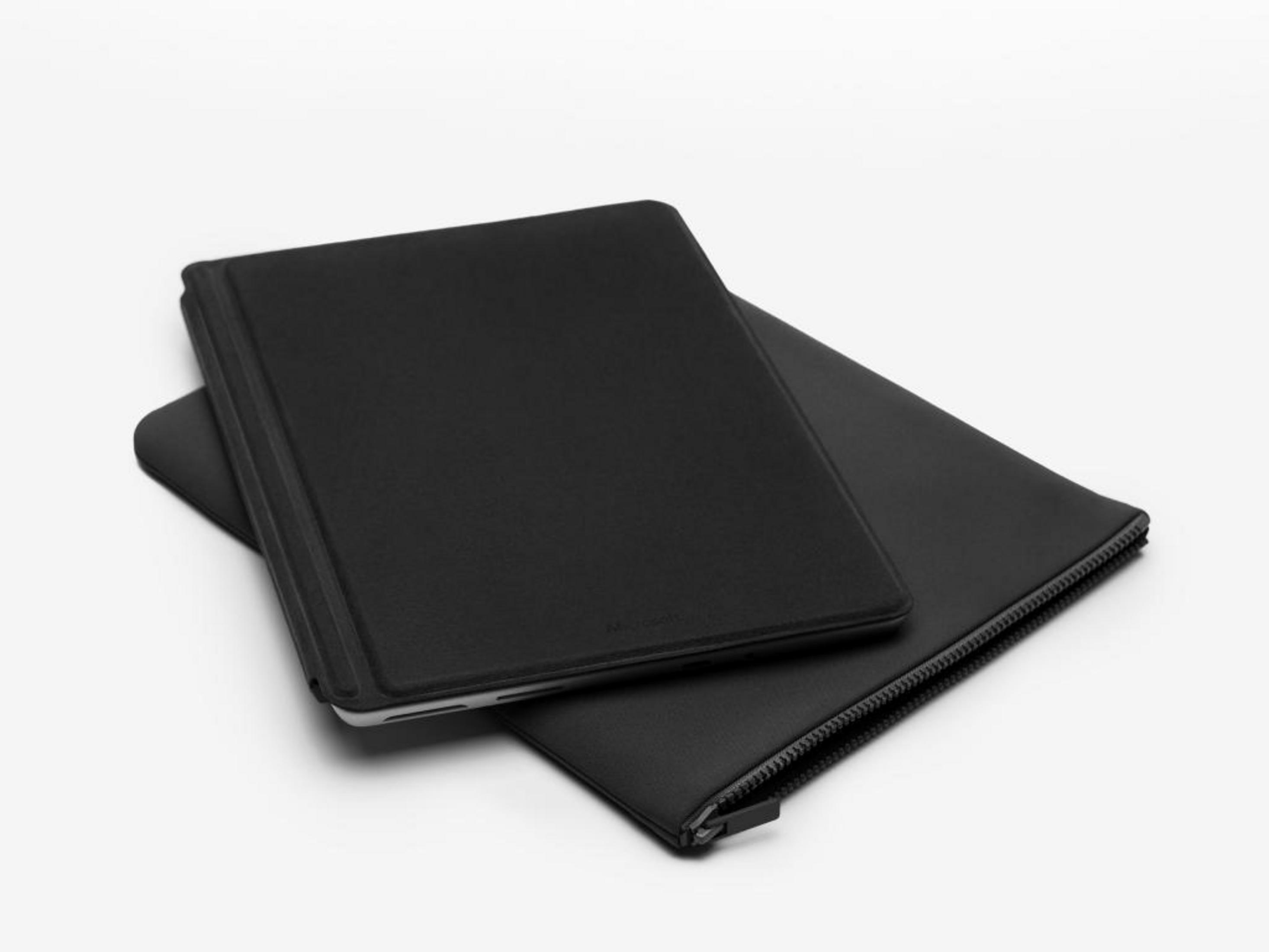 Una tableta negra con funda descansa sobre un estuche negro con cremallera.