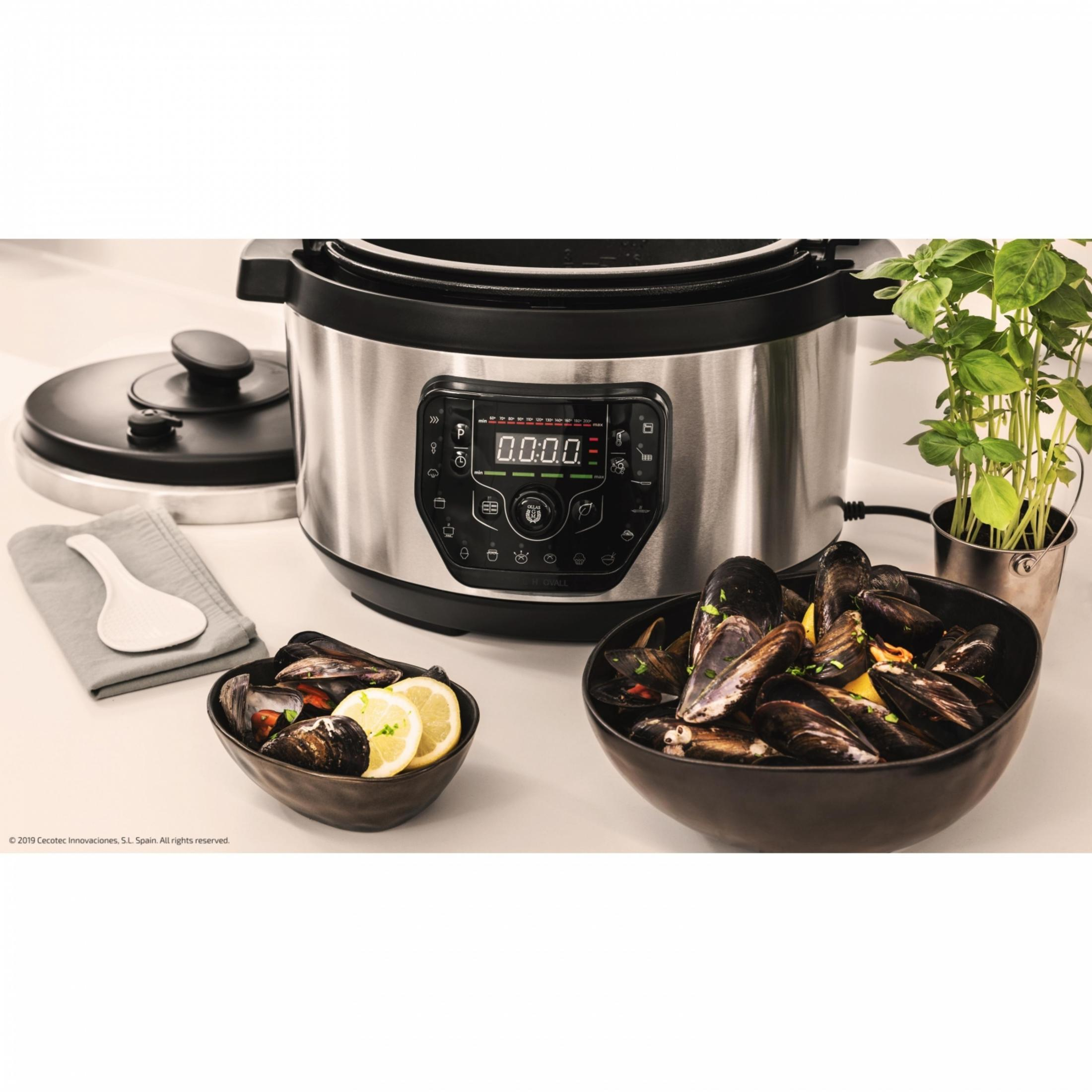 Una olla a presión con dos cuencos de mejillones y rodajas de limón.
