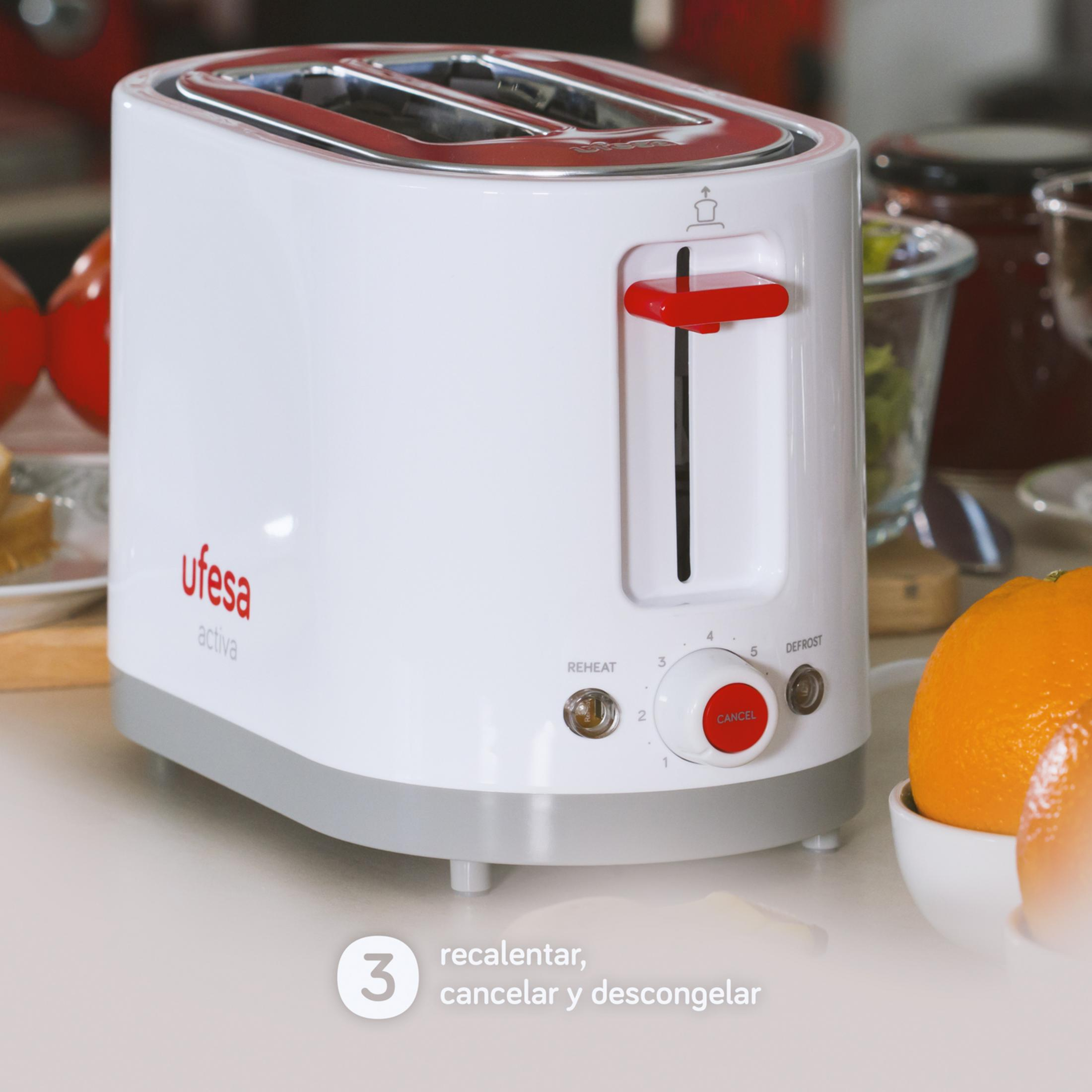 Ein weißer Toaster mit roten Akzenten steht auf einer Arbeitsplatte neben einer Orange.