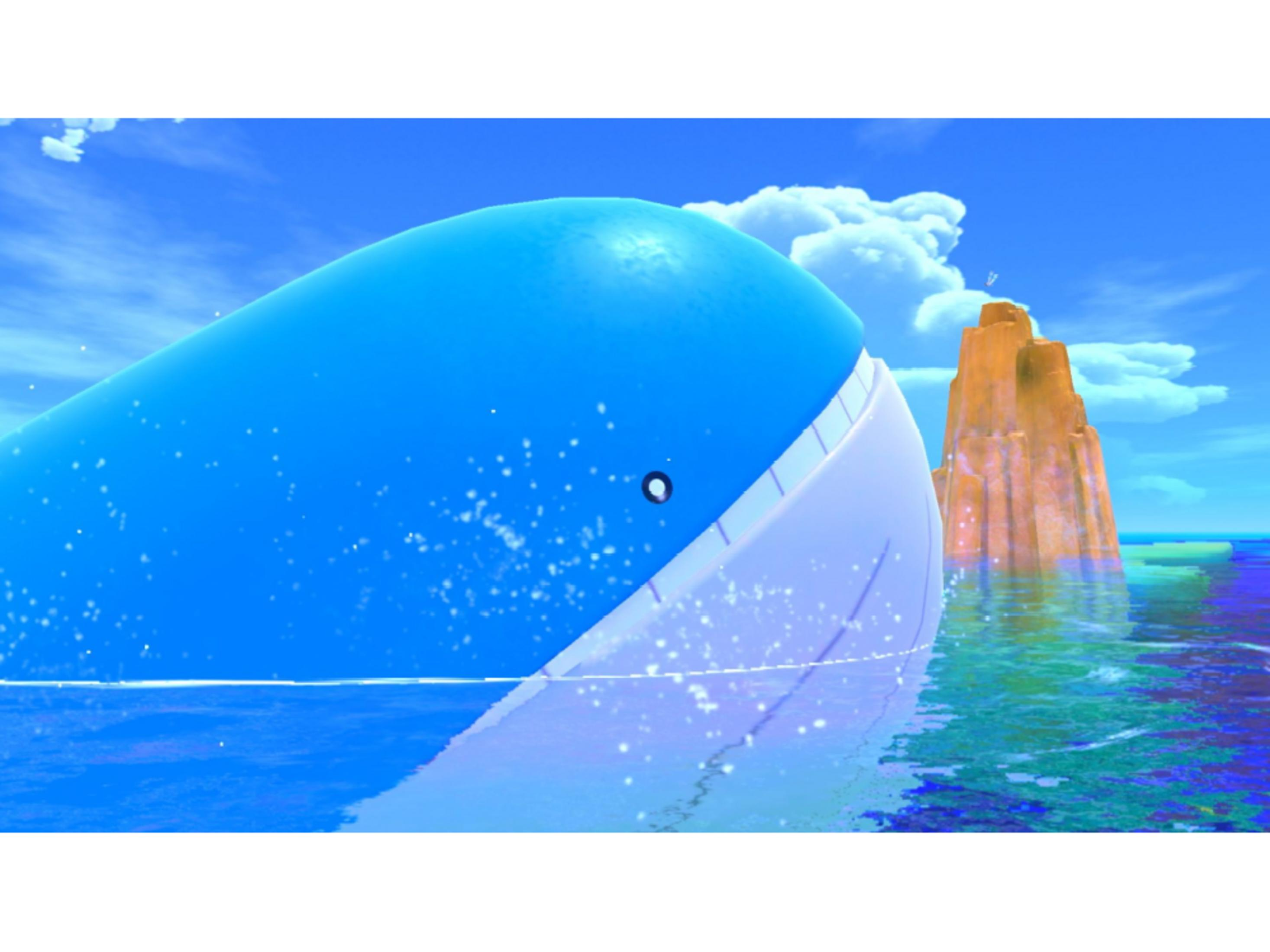 Una balena blu gigante nuota nell'oceano accanto a un'isola rocciosa arancione.