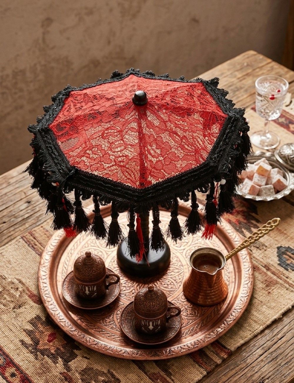 Kırmızı dantel şemsiye, Türk kahvesi fincanları ve cezve ile bakır tepsi üzerinde.