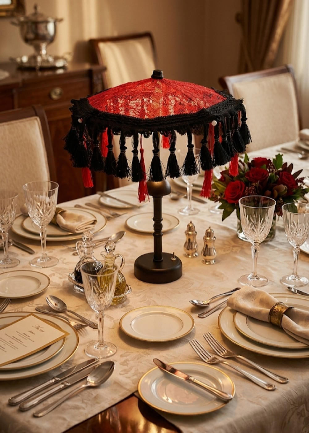 Kırmızı süslü lamba, çiçekler ve kristal bardaklarla donatılmış resmi yemek masası.