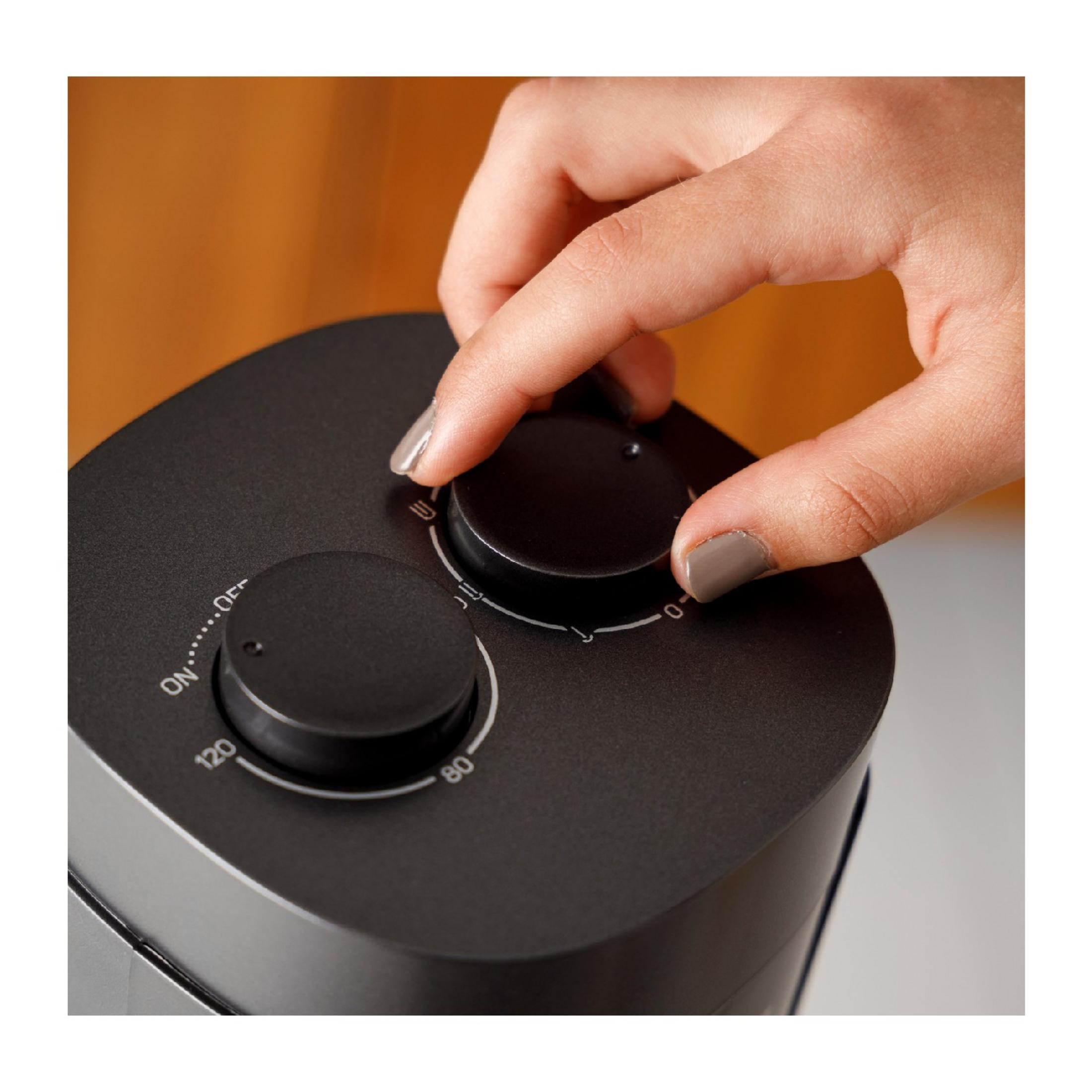 Una mano gira un dial giratorio negro en un dispositivo oscuro con marcas.