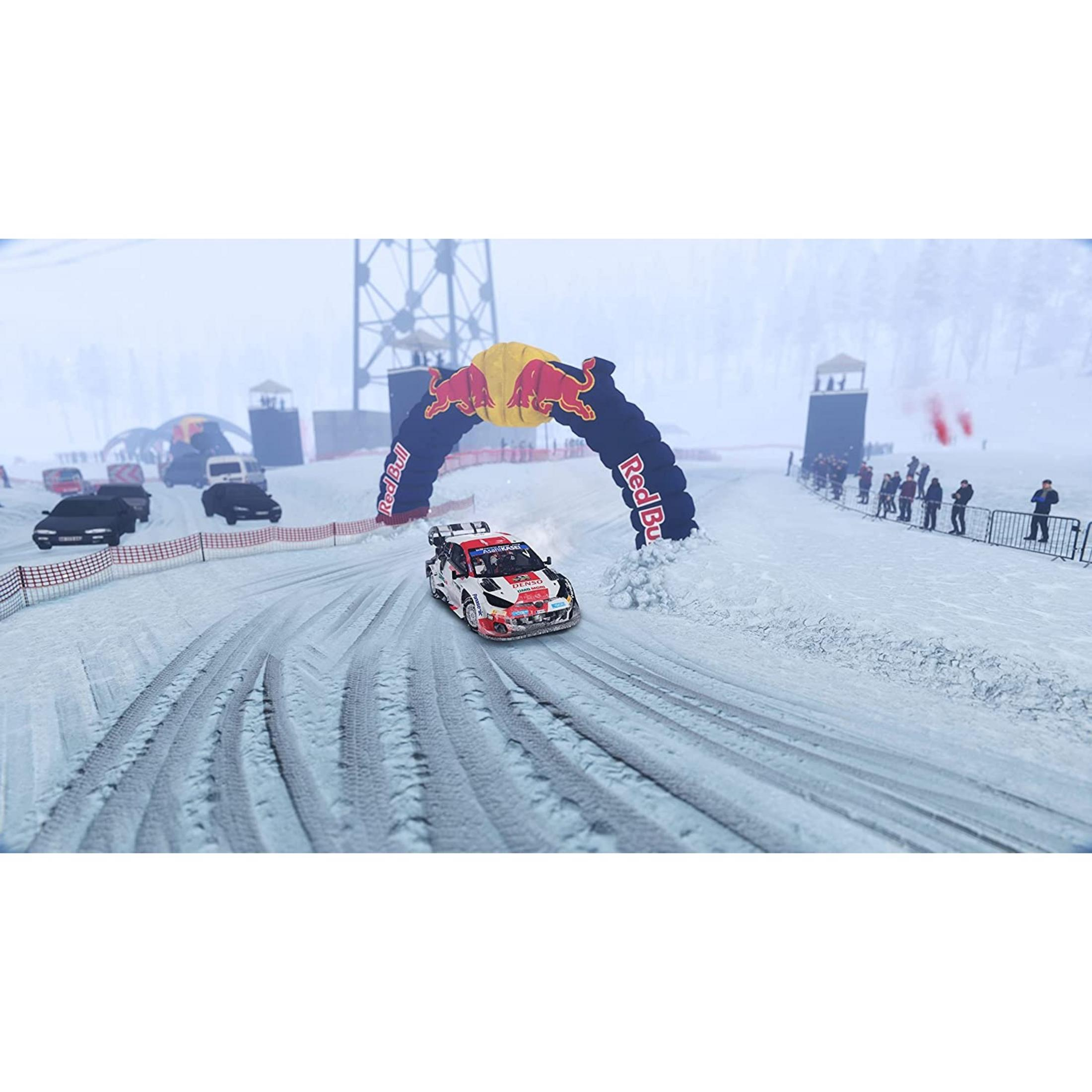 Un coche de rally pasa bajo un arco de Red Bull en una pista nevada.