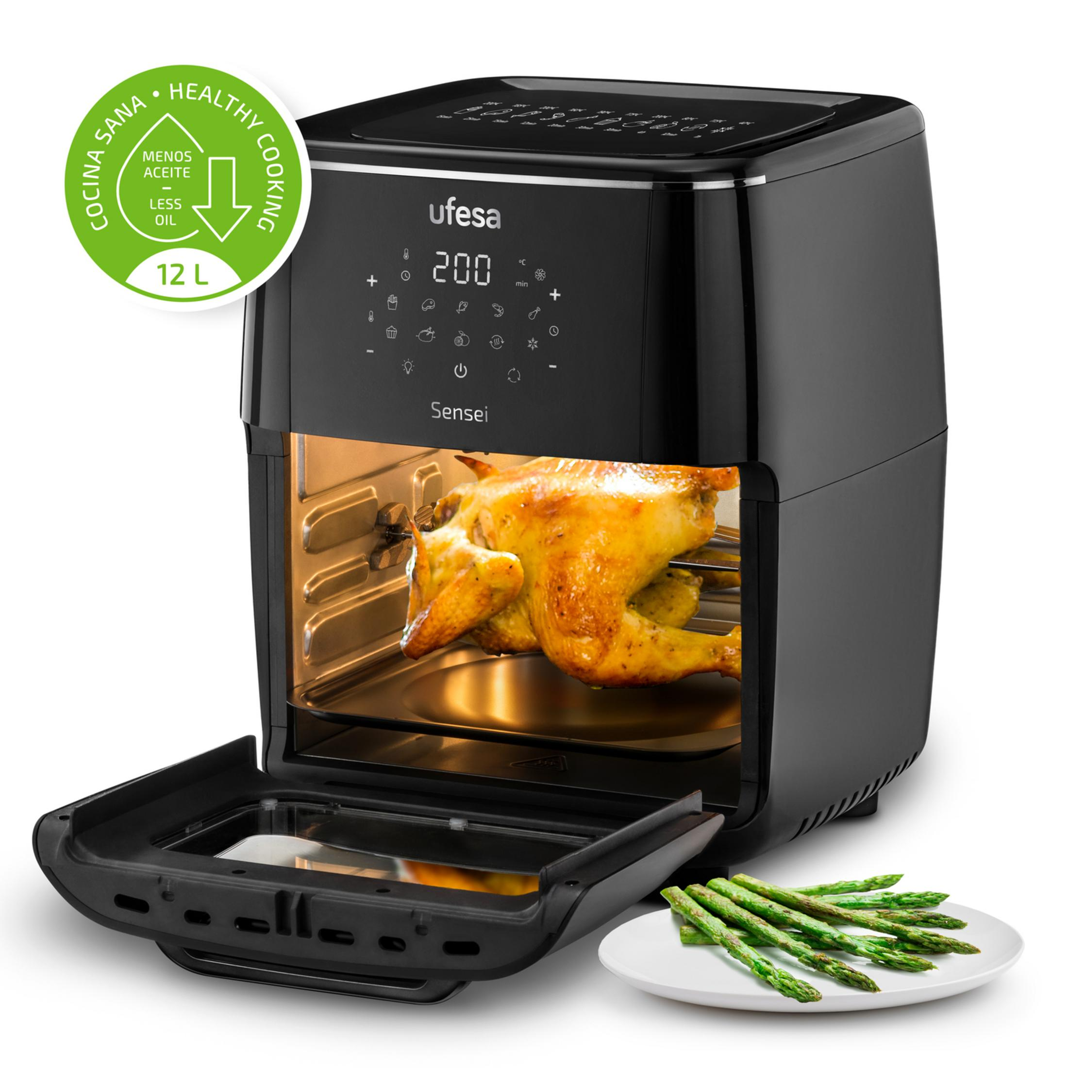 Una friggitrice ad aria nera con un pollo arrosto all'interno e asparagi accanto.