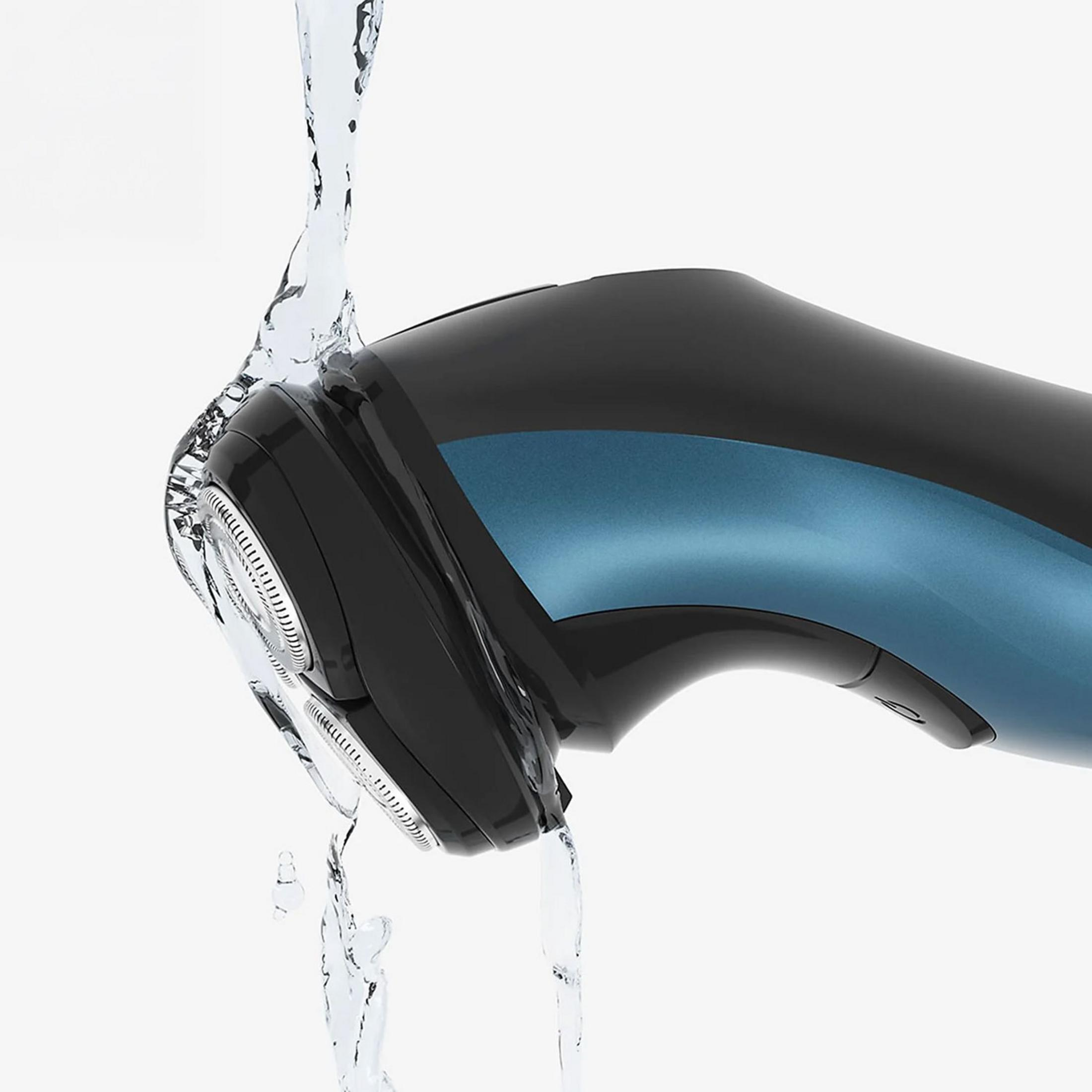 Un rasoio elettrico nero e blu sciacquato con acqua.