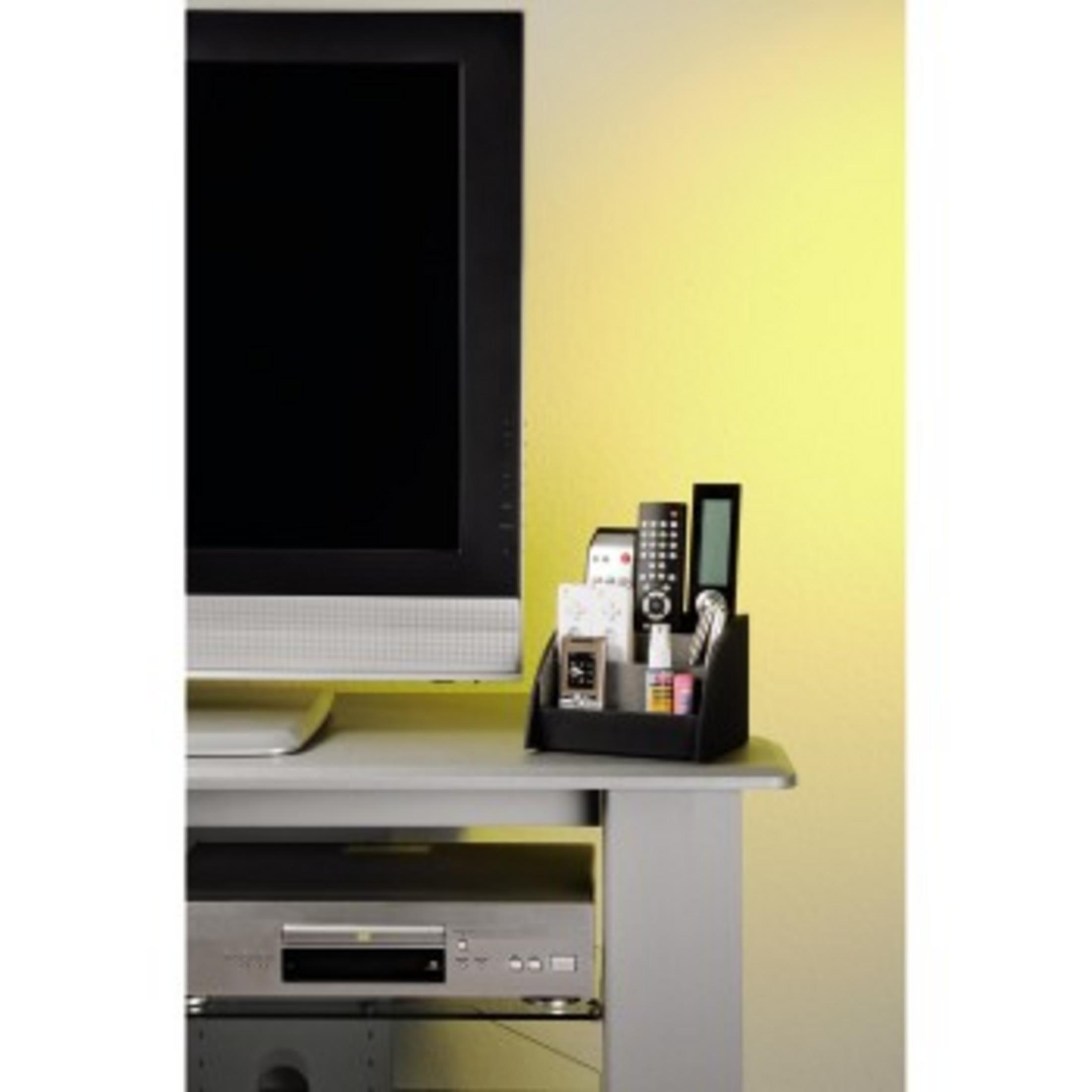 Ein schwarzer Organizer mit Fernbedienungen steht neben einem Fernseher.