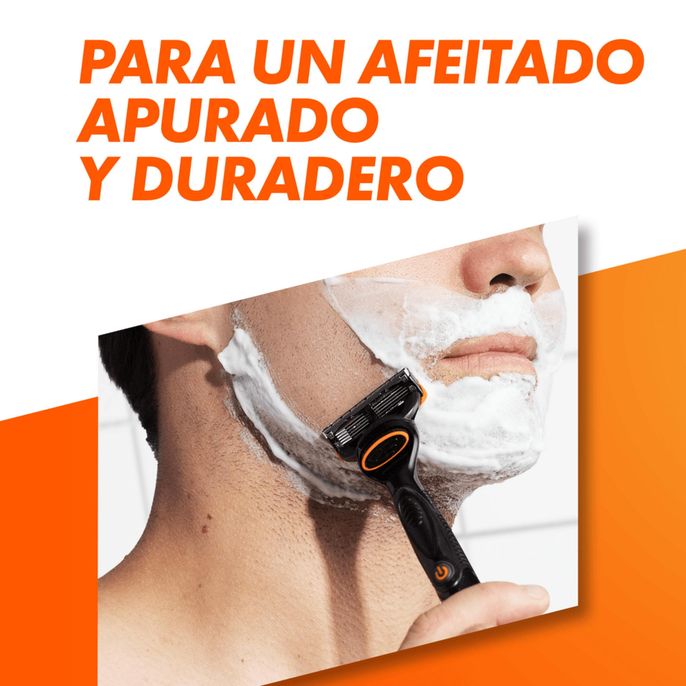 Hombre afeitándose la cara con espuma y maquinilla negra.